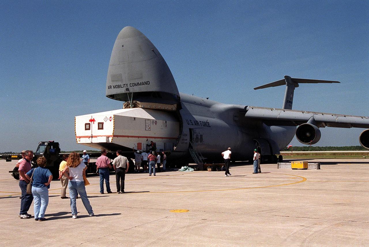 At the Shuttle Landing Facility, the crated Tracking and Data Relay Satellite (TDRS-H) is offloaded from an air cargo plane. It will be taken to the Spacecraft Assembly and Encapsulation Facility (SAEF-2) for testing. The TDRS is one of three (labeled H, I and J) being built in the Hughes Space and Communications Company Integrated Satellite Factory in El Segundo, Calif. The latest TDRS uses an innovative springback antenna design. A pair of 15-foot-diameter, flexible mesh antenna reflectors fold up for launch, then spring back into their original cupped circular shape on orbit. The new satellites will augment the TDRS system’s existing Sand Ku-band frequencies by adding Ka-band capability. TDRS will serve as the sole means of continuous, high-data-rate communication with the space shuttle, with the International Space Station upon its completion, and with dozens of unmanned scientific satellites in low earth orbit. The TDRS is scheduled to be launched from CCAFS June 29 aboard an Atlas IIA/Centaur rocket