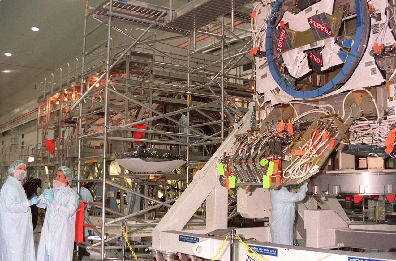 Workers at left stand by while work is done on the Integrated Truss Structure (ITS) Z1 at right. To the left of the Z1 is a high-gain antenna that will be installed on the Z1. An early exterior framework for the International Space Station, the Z1 will allow the first U.S. solar arrays, on mission STS-97, flight 4A, to be temporarily installed on Unity for early power. The Z1 is a payload scheduled on mission STS-92, the fifth flight to the Space Station, in the fall