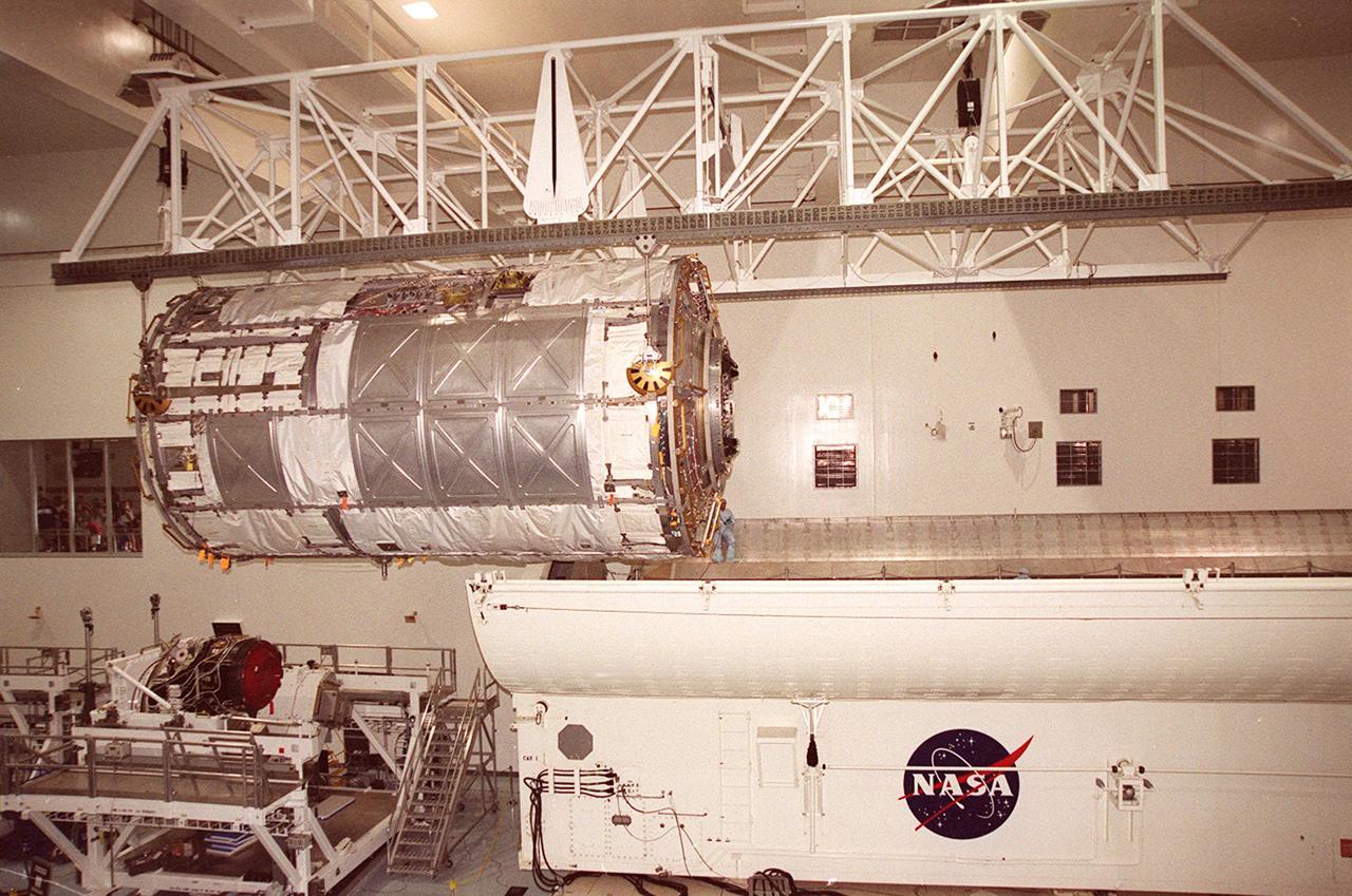 KENNEDY SPACE CENTER, FLA. -- In the Space Station Processing Facility (SSPF), the U.S. Laboratory Destiny, a component of the International Space Station, is moved to a payload canister for transfer to the Operations and Checkout Building where it will be tested in the altitude chamber. On the floor of the SSPF, left, is a Pressurized Mating Adapter-3. Destiny is scheduled to fly on mission STS-98 in early 2001. During the mission, the crew will install the Lab in the Space Station during a series of three space walks. The STS-98 mission will provide the Station with science research facilities and expand its power, life support and control capabilities. The U.S. Lab module continues a long tradition of microgravity materials research, first conducted by Skylab and later Shuttle and Spacelab missions. Destiny is expected to be a major feature in future research, providing facilities for biotechnology, fluid physics, combustion, and life sciences research