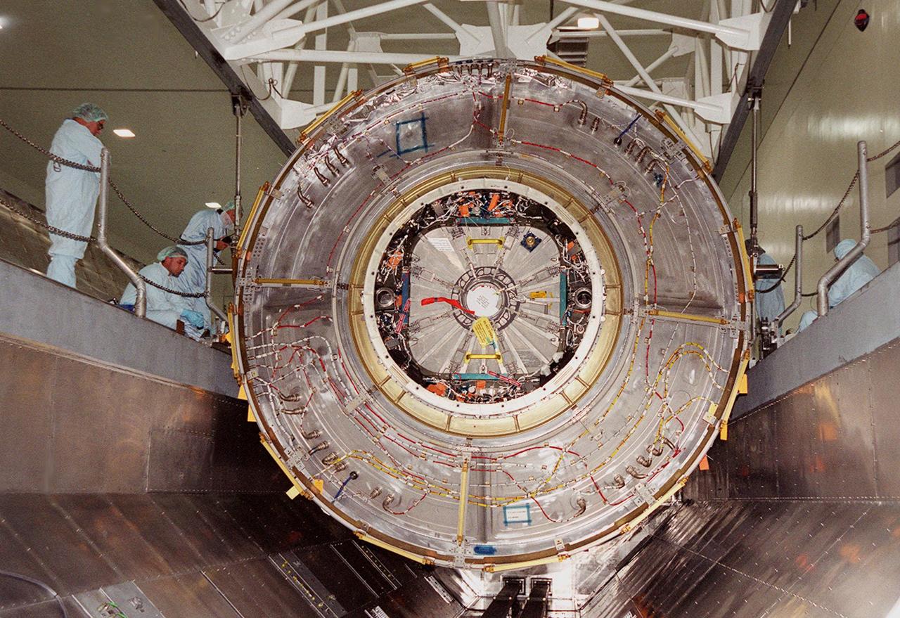 KENNEDY SPACE CENTER, FLA. -- Workers watch as the U.S. Laboratory Destiny, a component of the International Space Station, is lowered into a payload canister for transfer to the Operations and Checkout Building where it will be tested in the altitude chamber. Destiny is scheduled to fly on mission STS-98 in early 2001. During the mission, the crew will install the Lab in the Space Station during a series of three space walks. The STS-98 mission will provide the Station with science research facilities and expand its power, life support and control capabilities. The U.S. Lab module continues a long tradition of microgravity materials research, first conducted by Skylab and later Shuttle and Spacelab missions. Destiny is expected to be a major feature in future research, providing facilities for biotechnology, fluid physics, combustion, and life sciences research