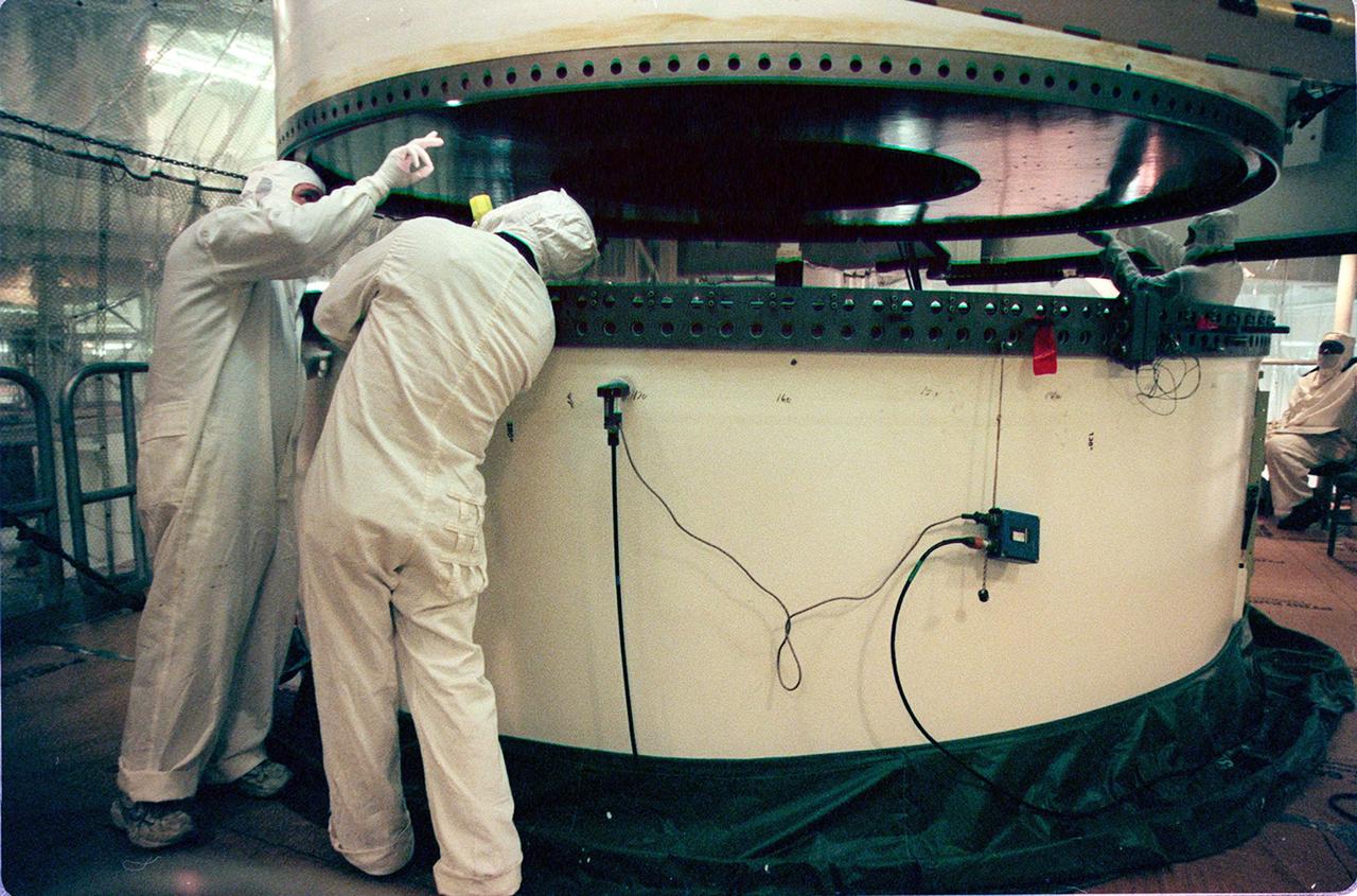 In the Vehicle Assembly Building, workers check the ring on the upper segment of a solid rocket booster (SRB) before mating it to the one below. The SRB is part of the stack for the STS-92 mission, scheduled for launch Oct. 5 from Launch Pad 39A