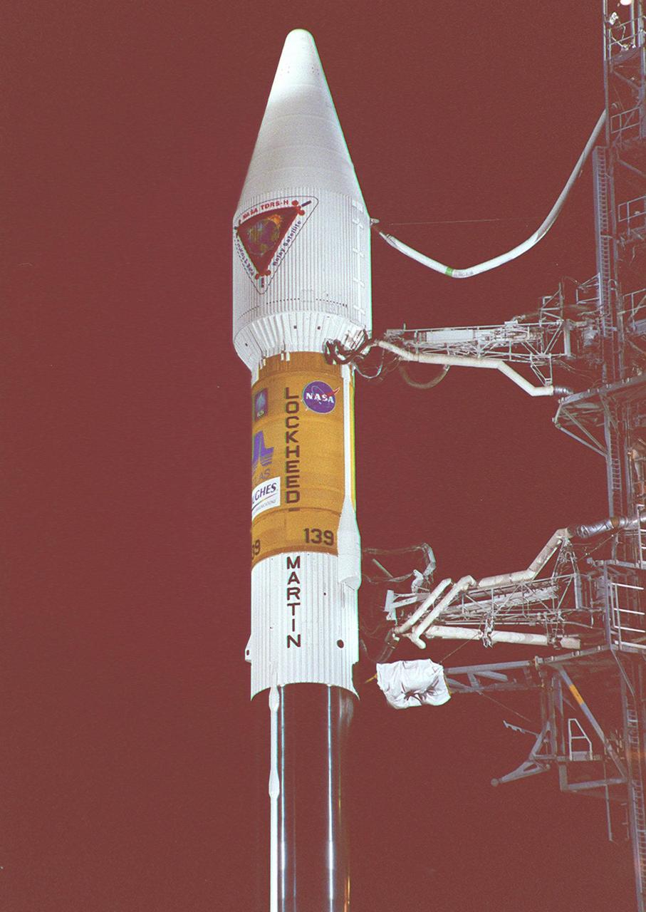 NASA’s Tracking and Data Relay Satellite (TDRS-H) sits poised on Launch Pad 36A, Cape Canaveral Air Force Station, before its scheduled launch aboard an Atlas IIA/Centaur rocket. One of three satellites (labeled H, I and J) being built by the Hughes Space and Communications Company, the latest TDRS uses an innovative springback antenna design. A pair of 15-foot-diameter, flexible mesh antenna reflectors fold up for launch, then spring back into their original cupped circular shape on orbit. The new satellites will augment the TDRS system’s existing Sand Ku-band frequencies by adding Ka-band capability. TDRS will serve as the sole means of continuous, high-data-rate communication with the space shuttle, with the International Space Station upon its completion, and with dozens of unmanned scientific satellites in low earth orbit