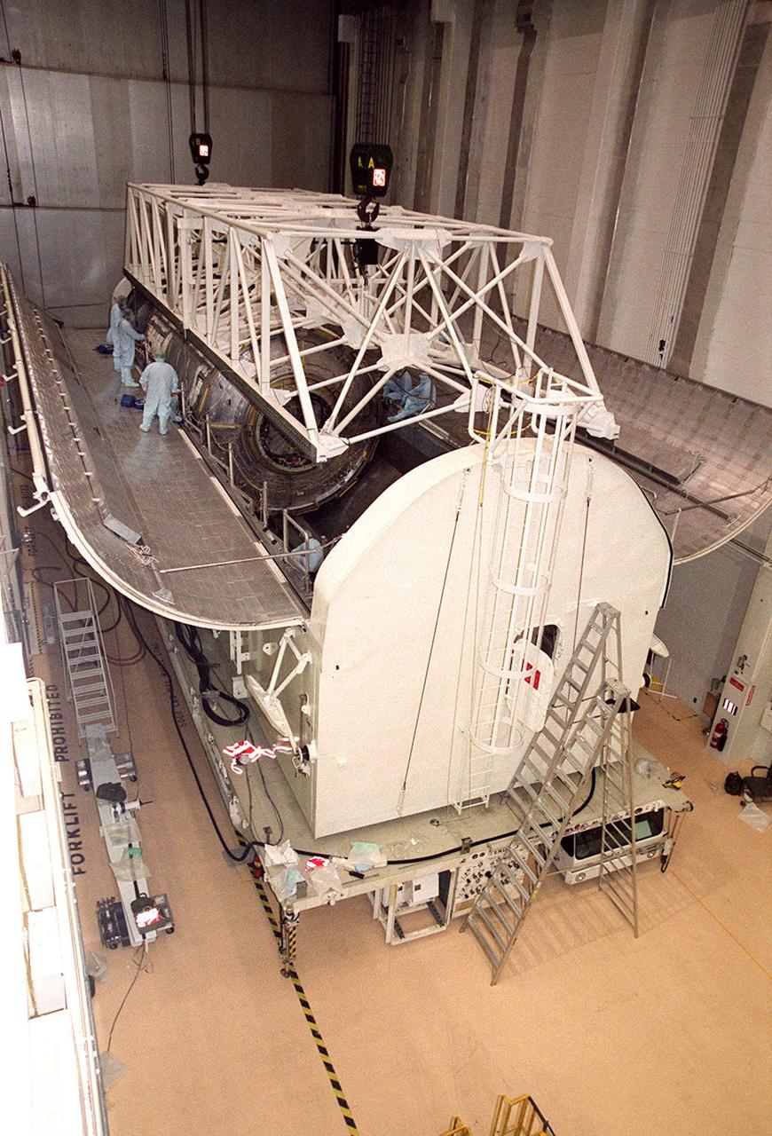 KENNEDY SPACE CENTER, FLA. -- In the Operations and Checkout Building (O&C), an overhead crane hovers over the U.S. Lab, named Destiny, while workers attach cables for lifting the Lab. The Lab will undergo testing in the altitude chamber in the O&C. Destiny is scheduled to fly on mission STS-98 in early 2001. During the mission, the crew will install the Lab in the Space Station during a series of three space walks. The STS-98 mission will provide the Station with science research facilities and expand its power, life support and control capabilities. The U.S. Lab module continues a long tradition of microgravity materials research, first conducted by Skylab and later Shuttle and Spacelab missions. Destiny is expected to be a major feature in future research, providing facilities for biotechnology, fluid physics, combustion, and life sciences research