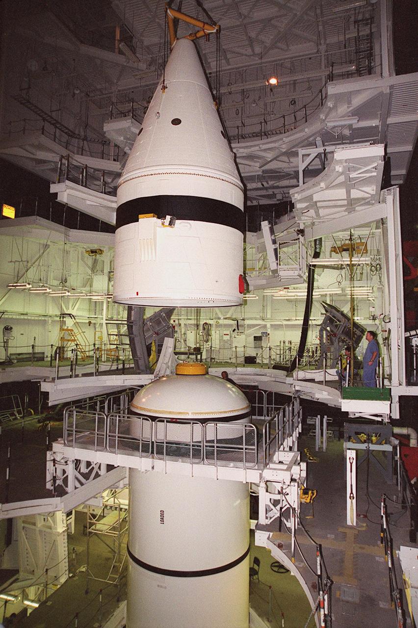 Inside the Vehicle Assembly Building, an overhead crane centers the forward section of a solid rocket booster (SRB) above the rest of the stack it will be mated to. The forward section of each booster, from nose cap to forward skirt contains avionics, a sequencer, forward separation motors, a nose cone separation system, drogue and main parachutes, a recovery beacon, a recovery light, a parachute camera on selected flights and a range safety system. Each SRB weighs approximately 1.3 million pounds at launch. The SRB is part of the stack for Space Shuttle Discovery and the STS-92 mission, scheduled for launch Oct. 5, from Launch Pad 39A, on the fifth flight to the International Space Station