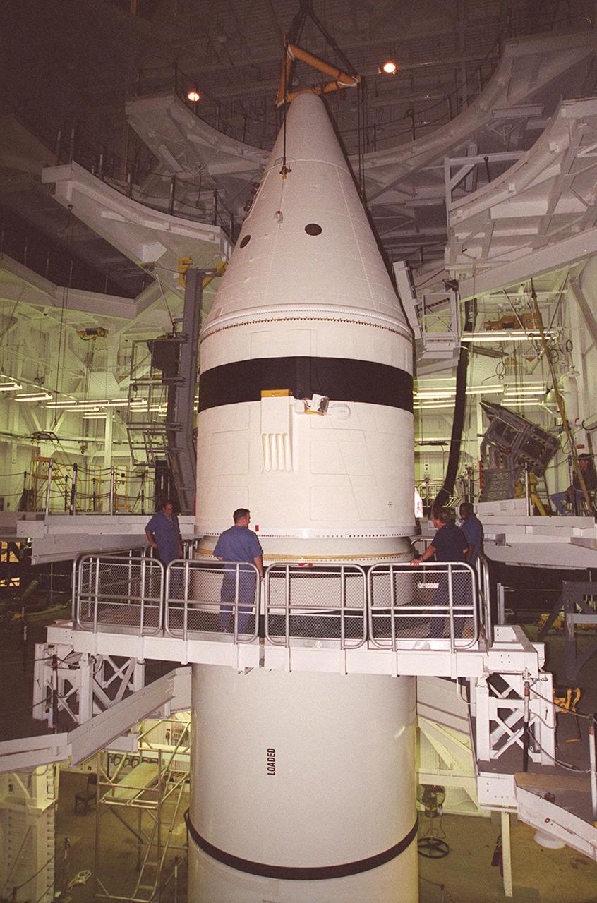 Inside the Vehicle Assembly Building, the forward section of a solid rocket booster (SRB) sits on top of the rest of the stack for mating. The forward section of each booster, from nose cap to forward skirt contains avionics, a sequencer, forward separation motors, a nose cone separation system, drogue and main parachutes, a recovery beacon, a recovery light, a parachute camera on selected flights and a range safety system. Each SRB weighs approximately 1.3 million pounds at launch. The SRB is part of the stack for Space Shuttle Discovery and the STS-92 mission, scheduled for launch Oct. 5, from Launch Pad 39A, on the fifth flight to the International Space Station