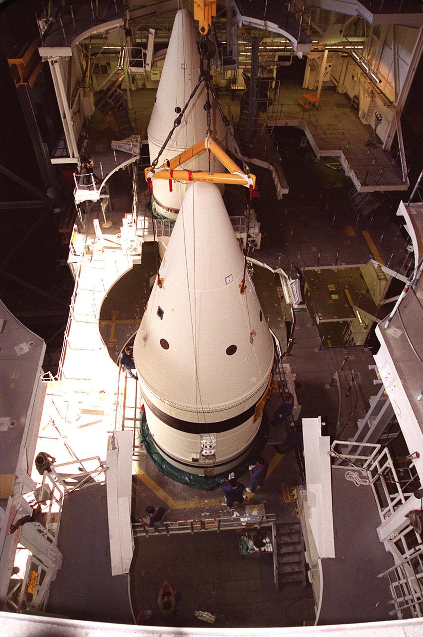 Workers in the Vehicle Assembly Building check the connections on the forward section of a solid rocket booster (SRB) being mated to the rest of the stack below it. The forward section of each booster, from nose cap to forward skirt contains avionics, a sequencer, forward separation motors, a nose cone separation system, drogue and main parachutes, a recovery beacon, a recovery light, a parachute camera on selected flights and a range safety system. Each SRB weighs approximately 1.3 million pounds at launch. The SRB is part of the stack for Space Shuttle Discovery and the STS-92 mission, scheduled for launch Oct. 5, from Launch Pad 39A, on the fifth flight to the International Space Station. Payloads on the mission include the Z-1 truss and Pressurized Mating Adapter-3, components of the Space Station