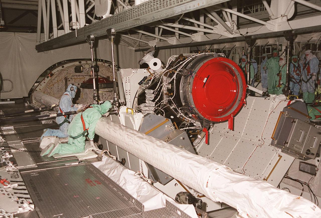 KENNEDY SPACE CENTER, FLA. -- In the Orbiter Processing Facility bay 1, workers check the placement of the Pressurized Mating Adapter -3 (PMA-3) as the overhead crane places it in the payload bay of the orbiter Discovery. A component of the International Space Station, the PMA-3 will fly on Shuttle mission STS-92, scheduled to launch Oct. 5. The mission will be the fifth flight to the Space Station, and the 100th Shuttle flight overall. PMA-3 provides shuttle docking port for solar array installation on flight 4A (mission STS-97 scheduled for Nov. 30), and Lab installation on flight 5A (mission STS-98, scheduled for Jan. 18, 2001)
