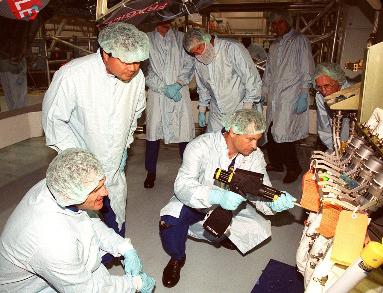 In the Space Station Processing Facility, members of the STS-92 crew check out equipment they will be using on the mission to the International Space Station. Here, (left to right) Mission Specialists Jeff Wisoff and Leroy Chiao watch while Michael Lopez-Alegria practices putting on and taking off fittings on the Z1 Integrated Truss Structure. In the background are Boeing technicians. The Z-1 truss, a component of the Station, is an early exterior framework to allow the first U.S. solar arrays on a future flight to be temporarily installed on Unity for early power. STS-92 is scheduled to launch Oct. 5 from launch Pad 39A
