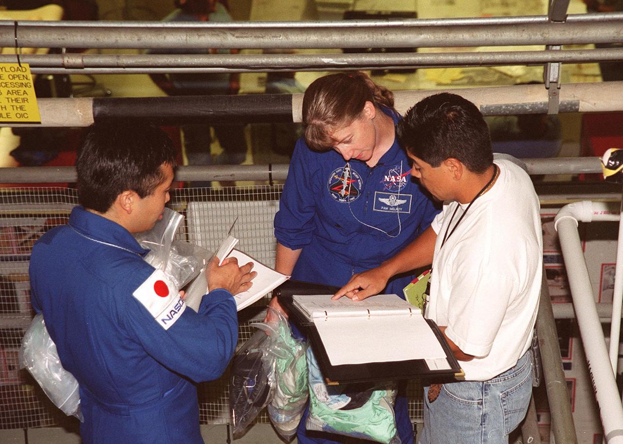 KENNEDY SPACE CENTER, FLA. -- During Crew Equipment Interface Test (CEIT) activities, STS-92 Mission Specialist Koichi Wakata, who is with the Japanese space agency, and Pilot Pam Melroy check paperwork in the Orbiter Processing Facility bay 1. At right is a Boeing worker. Other crew members taking part in the CEIT are Commander Brian Duffy and Mission Specialists Leroy Chiao, Jeff Wisoff, Michael Lopez-Alegria, and Bill McArthur. STS-92 is scheduled to launch Oct. 5 on Shuttle Discovery from Launch Pad 39A on the fifth flight to the International Space Station. Discovery will carry the Integrated Truss Structure (ITS) Z1, Pressurized Mating Adapter 3 (PMA-3), Ku-band Communications System, and Control Moment Gyros (CMGs)
