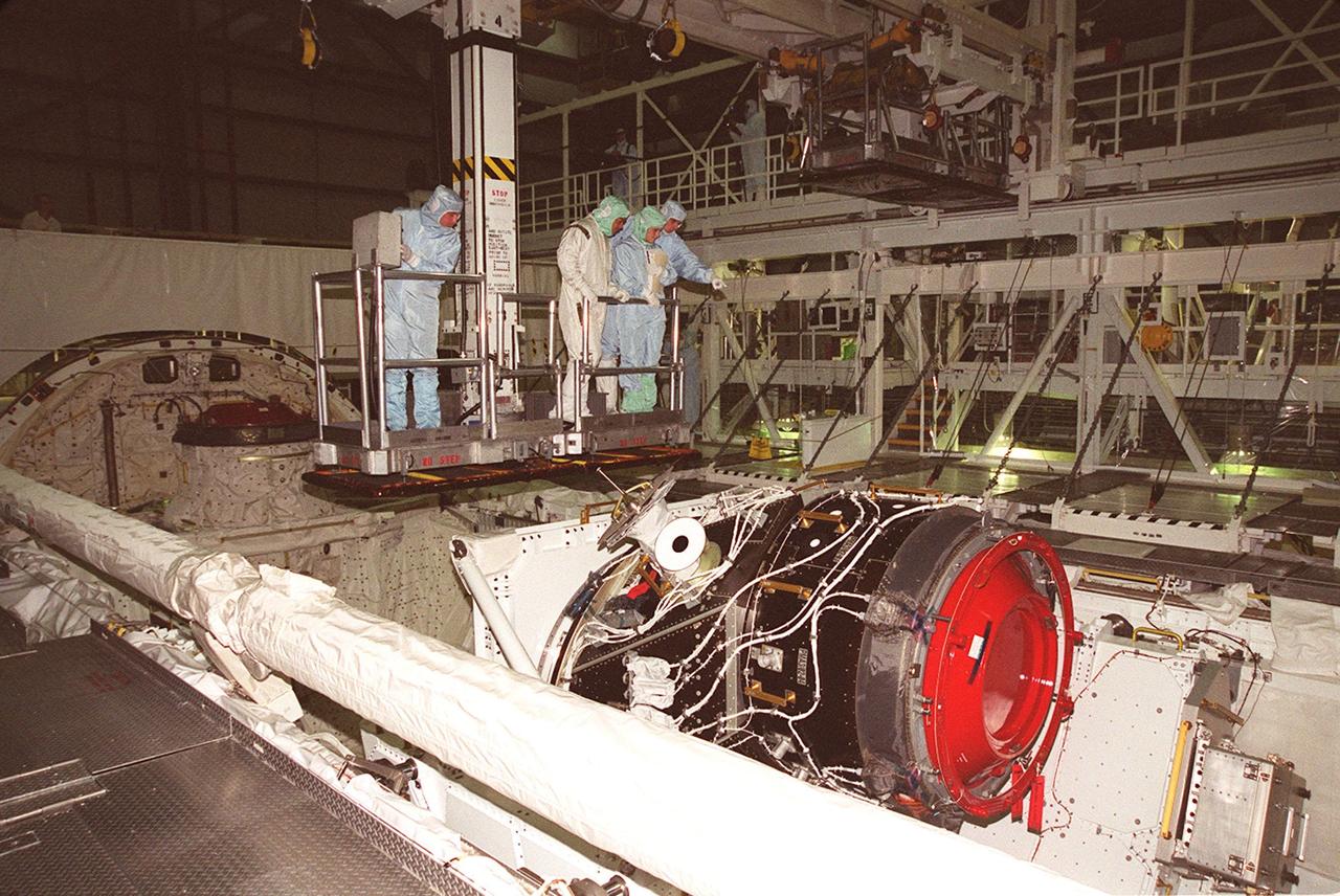 KENNEDY SPACE CENTER, FLA. -- In Orbiter Processing Facility bay 1, members of the STS-92 crew take part in Crew Equipment Interface Test (CEIT) activities. Being lowered into the payload bay of Discovery for a closer look at the payload are Mission Specialists Leroy Chiao (second from left) and Bill McArthur (far right), accompanied by Boeing workers. In the foreground is the Pressurized Mating Adapter-3 (PMA-3). Other crew members taking part in the CEIT are Commander Brian Duffy, Pilot Pam Melroy, and Mission Specialists Koichi Wakata, Jeff Wisoff and Michael Lopez-Alegria. STS-92 is scheduled to launch Oct. 5 on Shuttle Discovery from Launch Pad 39A on the fifth flight to the International Space Station. Discovery will carry the Integrated Truss Structure (ITS) Z1, the PMA-3, Ku-band Communications System, and Control Moment Gyros (CMGs)