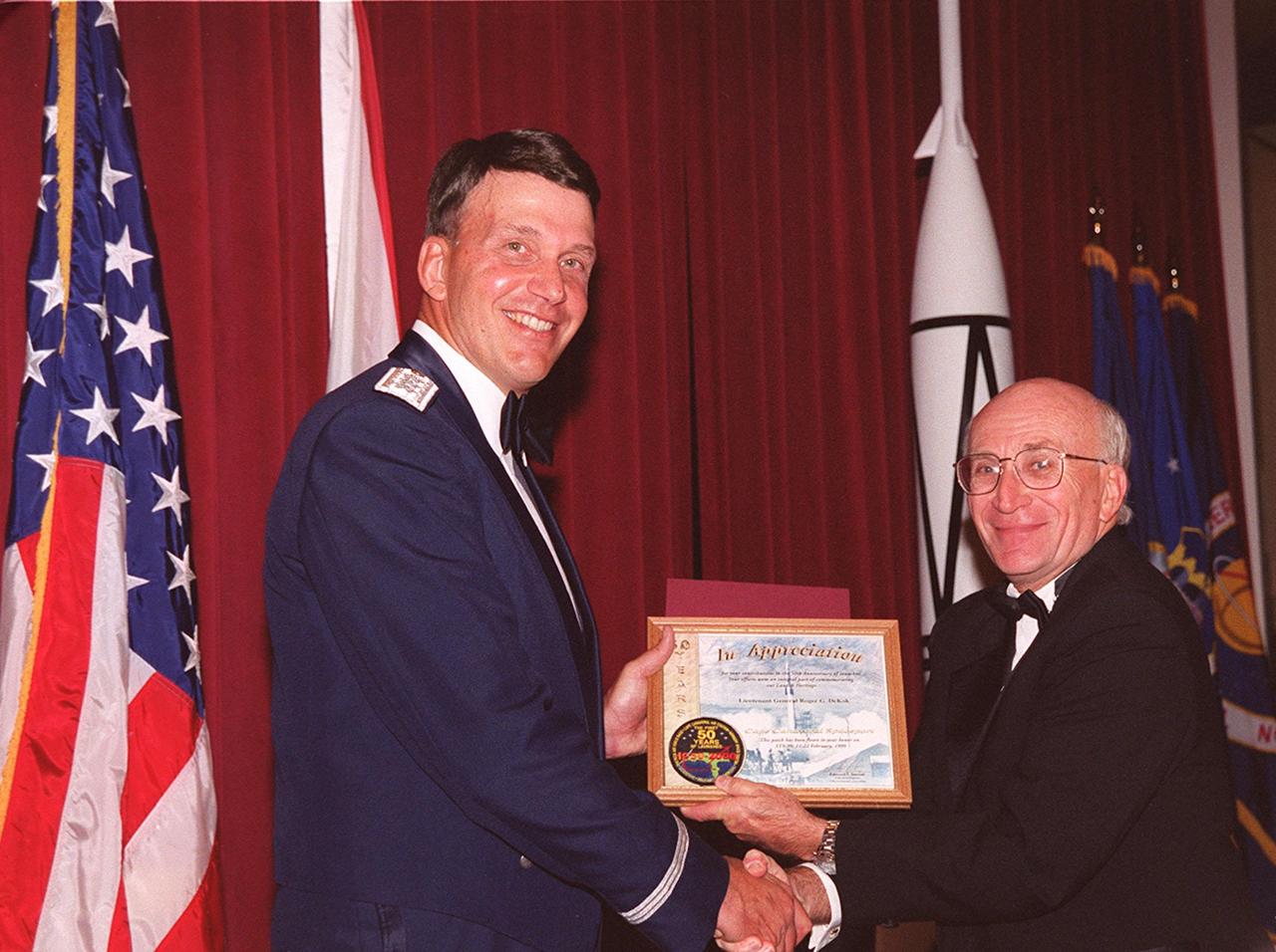 Vice Commander, Air Force Space Command, Lt. Gen. Roger DeKok (left) receives a commemorative plaque from Ed Gormel, committee chairman for the 50th anniversary gala that capped a year-long celebration of 50 years of rocket launches from Cape Canaveral Air Force Station. The first launch at CCAFS took place at 9:28 a.m. on July 24, 1950, with the liftoff of Bumper 8 from Launch Complex 3. The gala was hosted by the Cape Canaveral Chapter Air Force Association