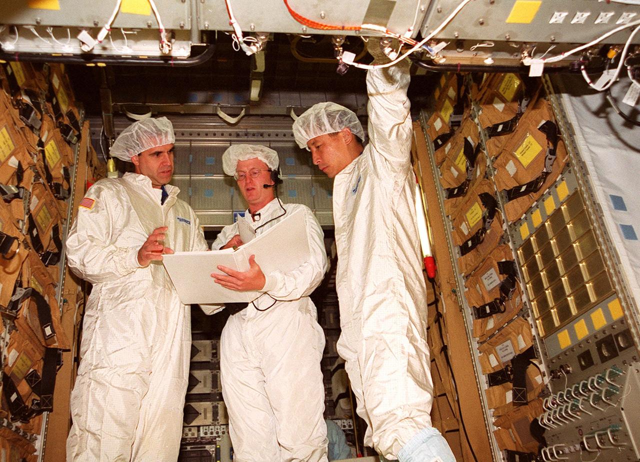 KENNEDY SPACE CENTER, FLA. -- Inside the SPACEHAB module, STS-106 Mission Specialists Richard A. Mastracchio (left) and Edward T. Lu (right) get information from a worker about the equipment in the module. They and other crew members Commander Terrence W. Wilcutt, Pilot Scott D. Altman, and Mission Specialists Boris V. Morukov, Yuri I. Malenchenko and Daniel C. Burbank are taking part Crew Equipment Interface Test activities at KSC. On the 11-day mission, the seven-member crew will perform support tasks on orbit, transfer supplies and prepare the living quarters in the newly arrived Zvezda Service Module for the first long-duration crew, dubbed “Expedition One,” which is due to arrive at the Station in late fall. STS-106 is scheduled to launch Sept. 8, 2000, at 8:31 a.m. EDT from Launch Pad 39B