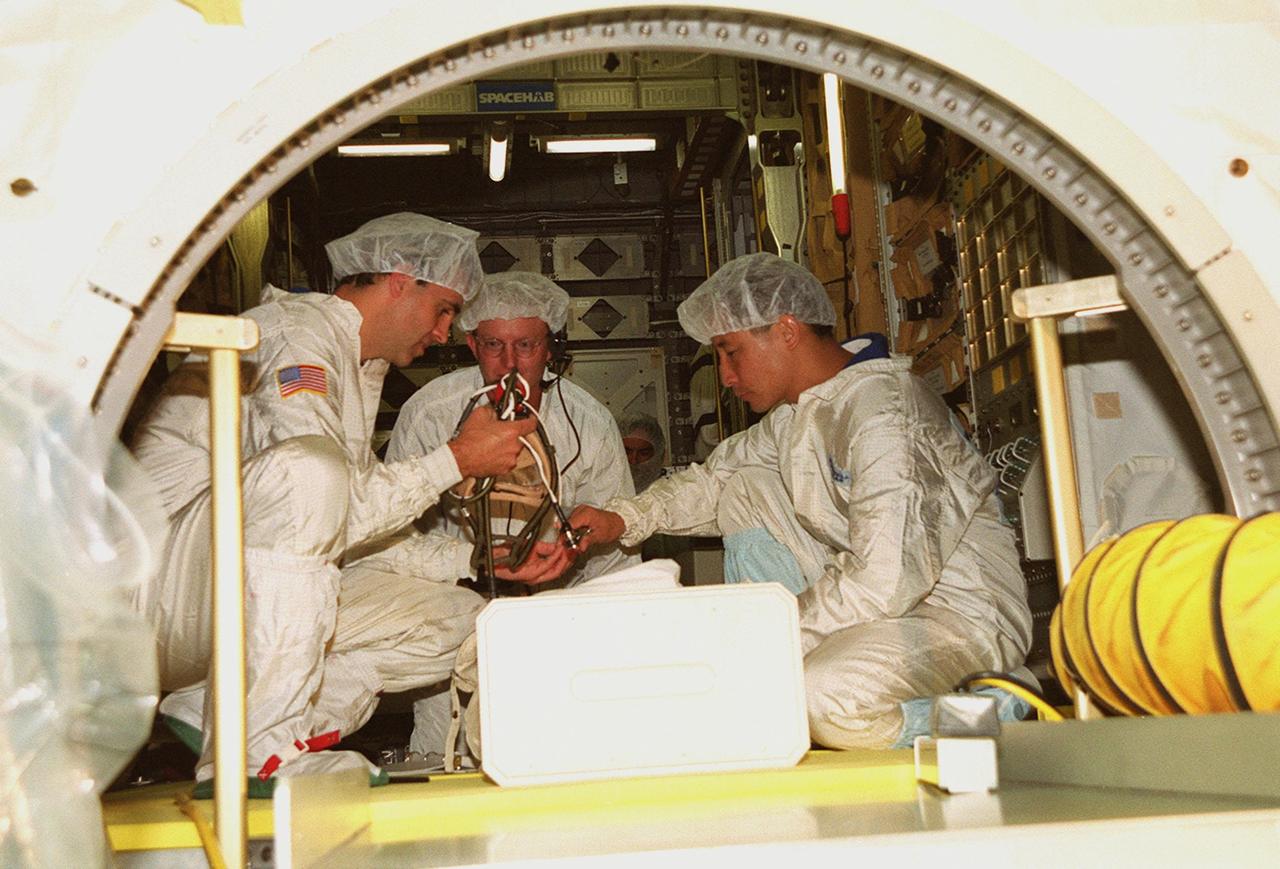 KENNEDY SPACE CENTER, FLA. -- Inside the SPACEHAB module, STS-106 Mission Specialists Richard A. Mastracchio (left) and Edward T. Lu (right) check out the equipment in the module that will fly on the mission. At center is a SPACEHAB worker. The two astronauts and other crew members Commander Terrence W. Wilcutt, Pilot Scott D. Altman, and Mission Specialists Boris V. Morukov, Yuri I. Malenchenko and Daniel C. Burbank are taking part Crew Equipment Interface Test activities at KSC. On the 11-day mission, the seven-member crew will perform support tasks on orbit, transfer supplies and prepare the living quarters in the newly arrived Zvezda Service Module for the first long-duration crew, dubbed “Expedition One,” which is due to arrive at the Station in late fall. STS-106 is scheduled to launch Sept. 8, 2000, at 8:31 a.m. EDT from Launch Pad 39B