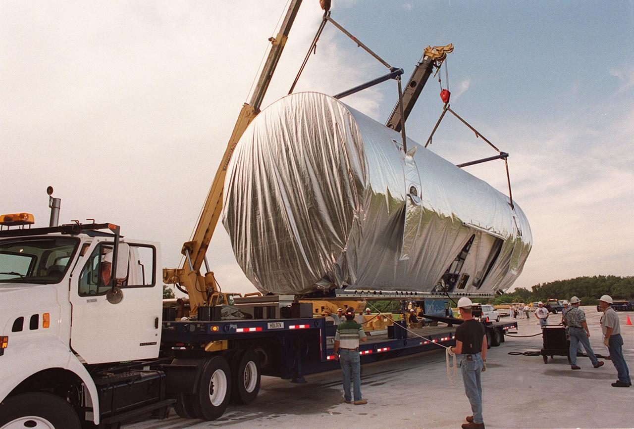 Workers oversee the placement of the P-1 truss, a component of the International Space Station, onto the bed of a transport vehicle that will move it to the Operations and Checkout Building for processing. The P-1 truss, scheduled to fly in spring of 2002, is part of a total 10-truss, girder-like structure on the Station that will ultimately extend the length of a football field. Astronauts will attach the 14-by-15 foot structure to the port side of the center truss, S0, during the spring assembly flight. The 33,000-pound P-1 will house the thermal radiator rotating joint (TRRJ) that will rotate the Station’s radiators away from the sun to increase their maximum cooling efficiency