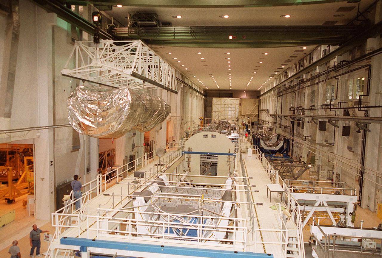 The P-1 truss, a component of the International Space Station, is moved the length of the Operations and Checkout Building to its work stand where it will undergo processing. Scheduled to fly in spring of 2002, the P-1 is part of a total 10-truss, girder-like structure on the Station that will ultimately extend the length of a football field. Astronauts will attach the 14-by-15 foot structure to the port side of the center truss, S0, during the spring assembly flight. The 33,000-pound P-1 will house the thermal radiator rotating joint (TRRJ) that will rotate the Station’s radiators away from the sun to increase their maximum cooling efficiency