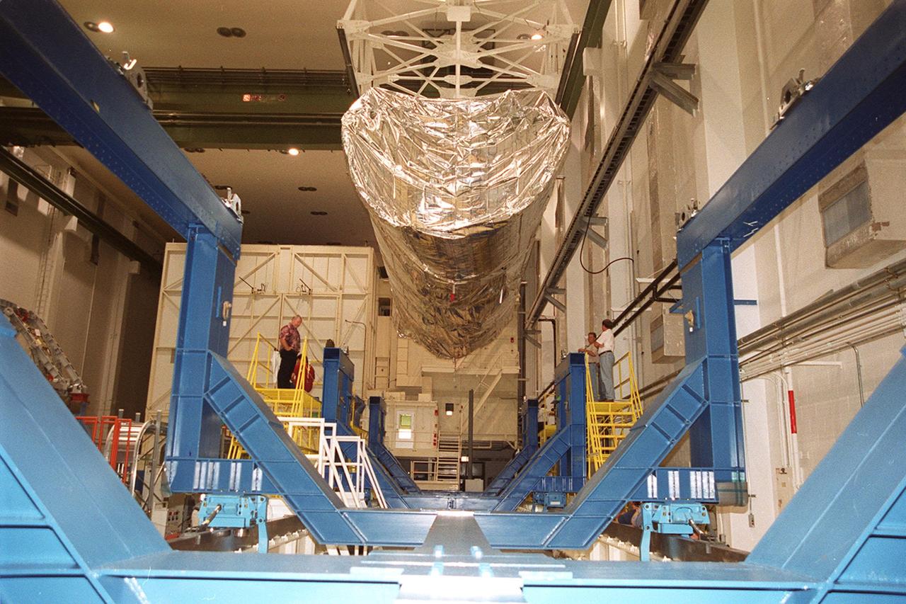 The P-1 truss (top of photo), a component of the International Space Station, nears its work stand in the Operations and Checkout Building where it will undergo processing. Scheduled to fly in spring of 2002, the P-1 is part of a total 10-truss, girder-like structure on the Station that will ultimately extend the length of a football field. Astronauts will attach the 14-by-15 foot structure to the port side of the center truss, S0, during the spring assembly flight. The 33,000-pound P-1 will house the thermal radiator rotating joint (TRRJ) that will rotate the Station’s radiators away from the sun to increase their maximum cooling efficiency