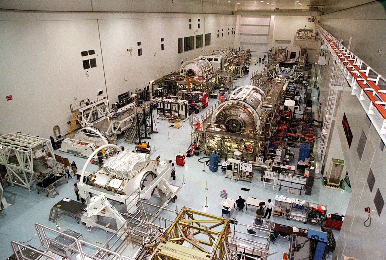 A wide-angle view of the floor of the Space Station Processing Facility. The floor is filled with racks and hardware for processing and testing the various components of the International Space Station (ISS). At the bottom left is the Zenith-1 (Z-1) Truss, the cornerstone truss of the Space Station. The Z-1 Truss was officially turned over to NASA from The Boeing Co. on July 31. The truss is scheduled to fly in Space Shuttle Discovery's payload pay on STS-92 targeted for launch Oct. 5, 2000. The Z-1 is considered a cornerstone truss because it carries critical components of the Station's attitude, communications, thermal and power control systems as well as four control moment gyros, high and low gain antenna systems, and two plasma contactor units used to disperse electrical charge build-ups. The Z-1 truss and a Pressurized Mating Adapter (PMA-3), also flying to the Station on the same mission, will be the first major U.S. elements flown to the ISS aboard the Shuttle since the launch of the Unity element in December 1998. The large module in the center of the floor is the U.S. Lab, Destiny. Expected to be a major feature in future research, Destiny will provide facilities for biotechnology, fluid physics, combustion, and life sciences research. It is scheduled to be launched on mission STS-98 (no date determined yet for launch)