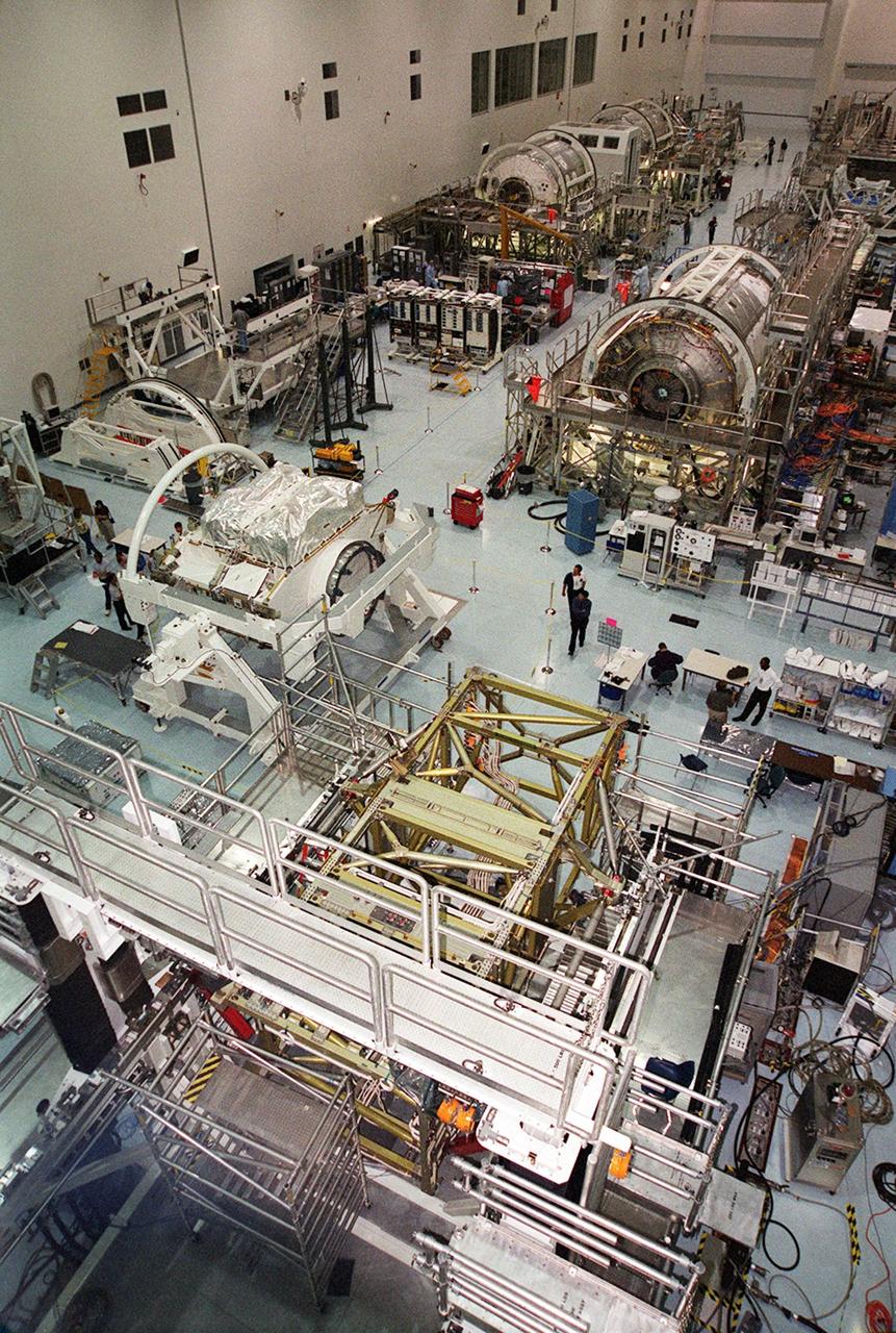 A wide-angle view of the floor of the Space Station Processing Facility. The floor is filled with racks and hardware for processing and testing the various components of the International Space Station (ISS). At center left is the Zenith-1 (Z-1) Truss, the cornerstone truss of the Space Station. The Z-1 Truss was officially turned over to NASA from The Boeing Co. on July 31. It is scheduled to fly in Space Shuttle Discovery's payload pay on STS-92 targeted for launch Oct. 5, 2000. The Z-1 is considered a cornerstone truss because it carries critical components of the Station's attitude, communications, thermal and power control systems as well as four control moment gyros, high and low gain antenna systems, and two plasma contactor units used to disperse electrical charge build-ups. The Z-1 truss and a Pressurized Mating Adapter (PMA-3), also flying to the Station on the same mission, will be the first major U.S. elements flown to the ISS aboard the Shuttle since the launch of the Unity element in December 1998. The large module in the upper right hand corner of the floor is the U.S. Lab, Destiny. Expected to be a major feature in future research, Destiny will provide facilities for biotechnology, fluid physics, combustion, and life sciences research. It is scheduled to be launched on mission STS-98 (no date determined yet for launch)