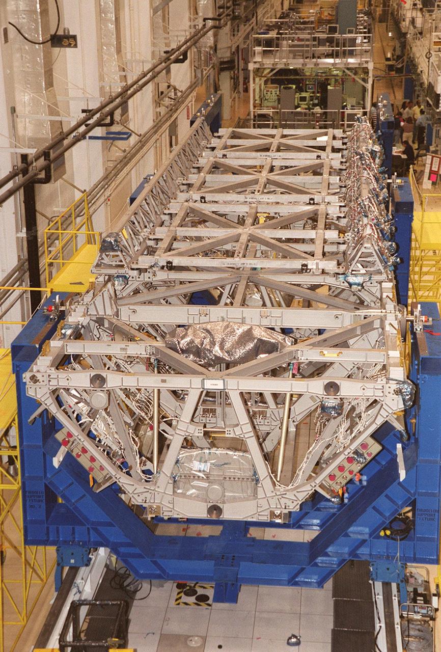 The length of the P-1 truss is seen as it rests in a workstand in the Operations and Checkout Building. Scheduled to fly in spring of 2002, the P-1 is part of a total 10-truss, girder-like structure that will ultimately extend the length of a football field. Astronauts will attach the 14by 15-foot structure to the port side of the center truss, S0, during the spring assembly flight. The 33,000-pound P-1 will house the thermal radiator rotating joint (TRRJ) that will rotate the International Space Station’s radiators away from the sun to increase their maximum cooling efficiency