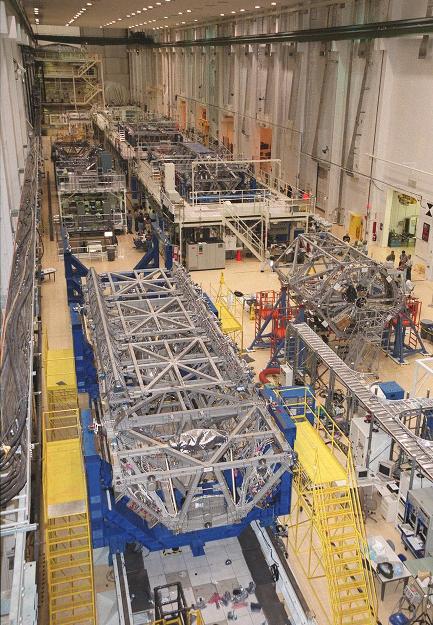  In the foreground is the P-1 truss, resting in a blue workstand in the long, crowded Operations and Checkout Building. Scheduled to fly in spring of 2002, the P-1 is part of a total 10-truss, girder-like structure that will ultimately extend the length of a football field. Astronauts will attach the 14by 15-foot structure to the port side of the center truss, S0, during the spring assembly flight. The 33,000-pound P-1 will house the thermal radiator rotating joint (TRRJ) that will rotate the International Space Station’s radiators away from the sun to increase their maximum cooling efficiency