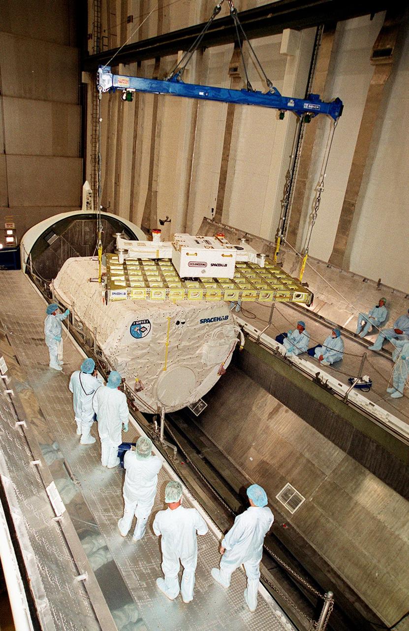 KENNEDY SPACE CENTER, FLA. -- In the Space Station Processing Facility, workers maneuver the Integrated Cargo Carrier (ICC) toward the opening in the payload canister. The canister already has the SPACEHAB module stowed. The canister will transport its cargo to Launch Pad 39B in preparation for mission STS-106, scheduled to launch Sept. 8 at 8:31 a.m. EDT. During the mission to the International Space Station, the crew will complete service module support tasks on orbit, transfer supplies and outfit the Space Station for the first long-duration crew