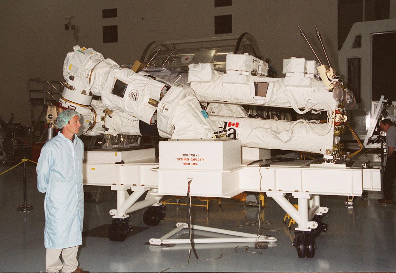 The Canadian Space Agency’s Space Station Remote Manipulator System (SSRMS) sits on the floor of the Space Station Processing Facility before transfer to a test stand . The 56-foot-long arm will be the primary means of transferring payloads between the orbiter payload bay and the International Space Station. Its three segments comprise seven joints for highly flexible land precise movement, making it capable of moving around the Station’s exterior like an inchworm. The SSRMS is scheduled for launch on STS-100 in April 2001