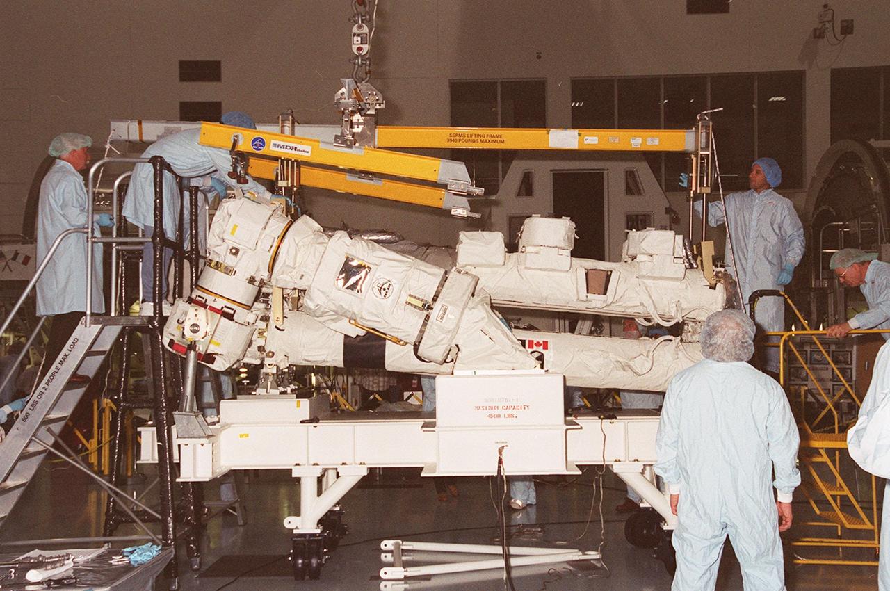 Workers in the Space Station Processing Facility attach an overhead crane to the Canadian Space Agency’s Space Station Remote Manipulator System (SSRMS). The crane will lift and transfer the SSRMS to a test stand where it will be mated to its payload carrier. This pallet will later be installed into the payload bay of Space Shuttle Endeavour for launch to the International Space Station on STS-100 in April 2001. The 56-foot-long arm will be the primary means of transferring payloads between the orbiter payload bay and the Station. Its three segments comprise seven joints for highly flexible land precise movement, making it capable of moving around the Station’s exterior like an inchworm