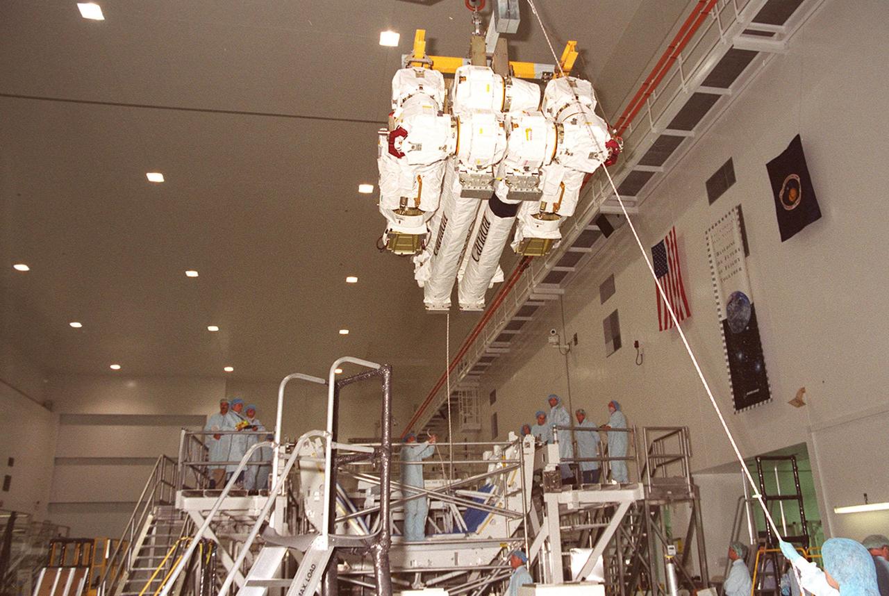 Workers in the Space Station Processing Facility help guide the Canadian Space Agency’s Space Station Remote Manipulator System (SSRMS) suspended from an overhead crane. The SSRMS is being moved to a test stand where it will be mated to its payload carrier. This pallet will later be installed into the payload bay of Space Shuttle Endeavour for launch to the International Space Station on STS-100 in April 2001. The 56-foot-long arm will be the primary means of transferring payloads between the orbiter payload bay and the Station. Its three segments comprise seven joints for highly flexible land precise movement, making it capable of moving around the Station’s exterior like an inchworm