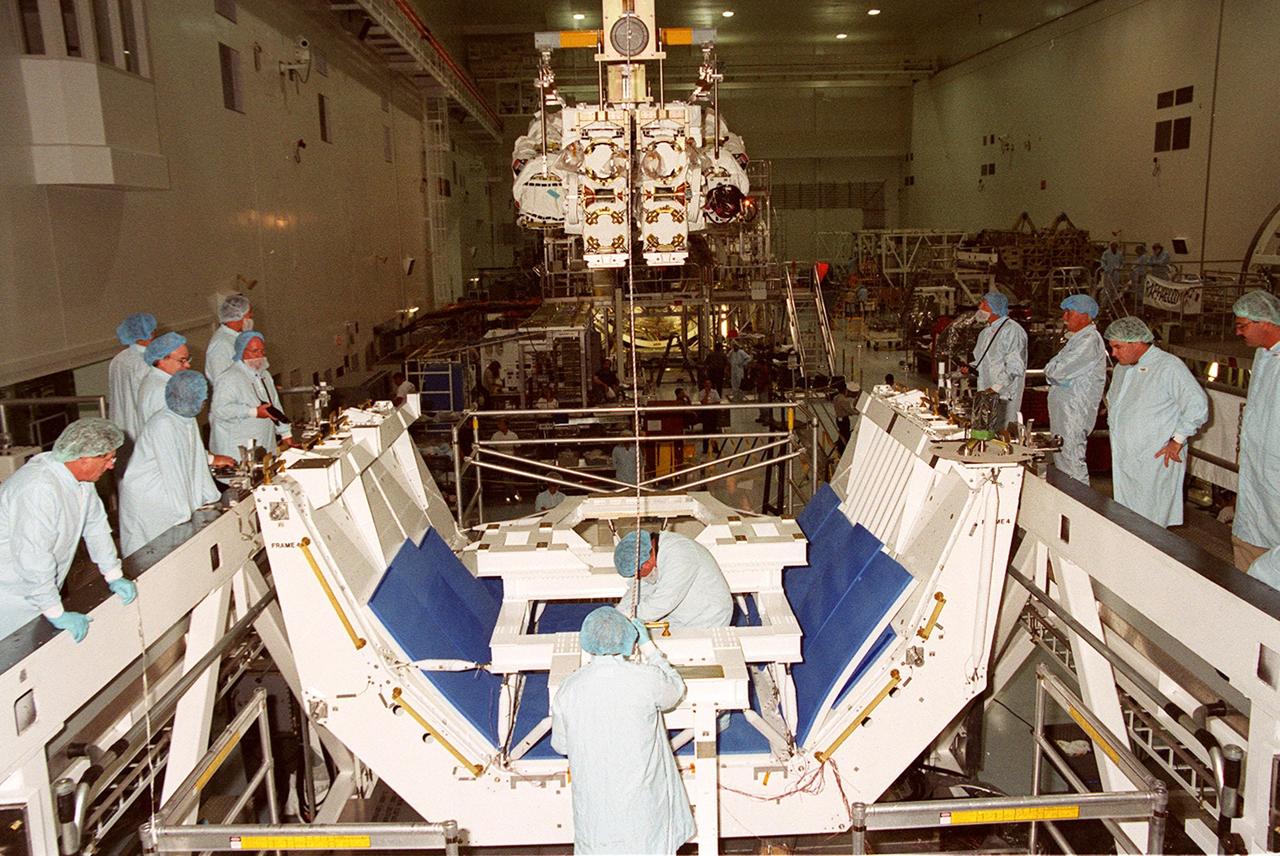 In the Space Station Processing Facility, the Canadian Space Agency’s Space Station Remote Manipulator System (SSRMS), suspended from an overhead crane, zeroes in on its destination, the test stand below. At the test stand the SSRMS it will be mated to its payload carrier. This pallet will later be installed into the payload bay of Space Shuttle Endeavour for launch to the International Space Station on STS-100 in April 2001. The 56-foot-long arm will be the primary means of transferring payloads between the orbiter payload bay and the Station. Its three segments comprise seven joints for highly flexible land precise movement, making it capable of moving around the Station’s exterior like an inchworm