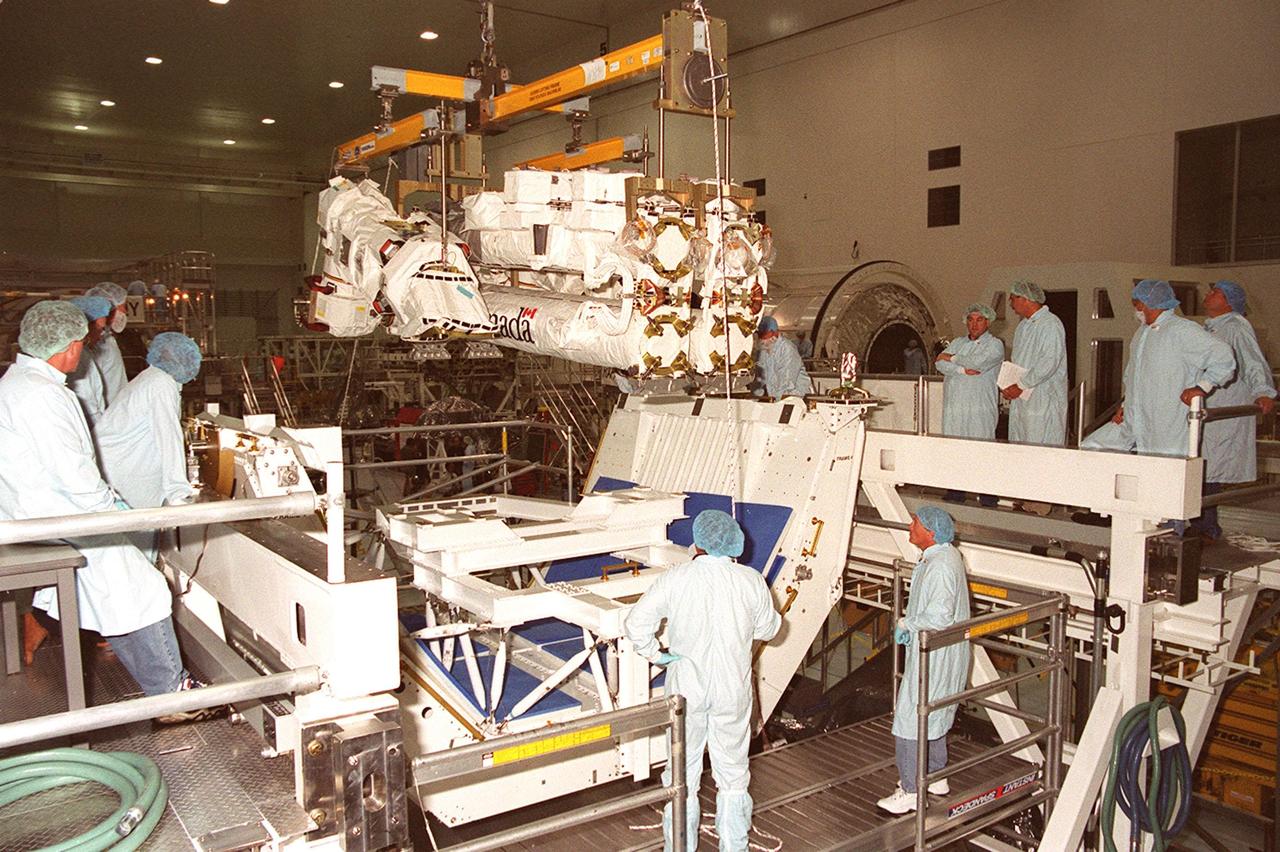 With gentle guidance, the Canadian Space Agency’s Space Station Remote Manipulator System (SSRMS) is lowered by crane onto a test stand in the Space Station Processing Facility. At the test stand the SSRMS it will be mated to its payload carrier. This pallet will later be installed into the payload bay of Space Shuttle Endeavour for launch to the International Space Station on STS-100 in April 2001. The 56-foot-long arm will be the primary means of transferring payloads between the orbiter payload bay and the Station. Its three segments comprise seven joints for highly flexible land precise movement, making it capable of moving around the Station’s exterior like an inchworm