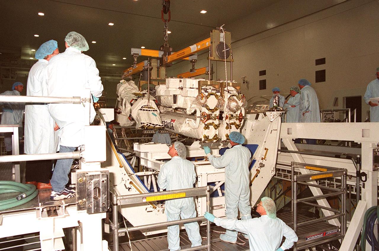 Workers in the Space Station Processing Facility help maneuver the Space Station Remote Manipulator System (SSRMS) onto a test stand. A component of the International Space Station provided by the Canadian Space Agency, the SSRMS will be mated to its payload carrier and later installed into the payload bay of Space Shuttle Endeavour for launch to the Station on STS-100 in April 2001. The 56-foot-long arm will be the primary means of transferring payloads between the orbiter payload bay and the Station. Its three segments comprise seven joints for highly flexible land precise movement, making it capable of moving around the Station’s exterior like an inchworm