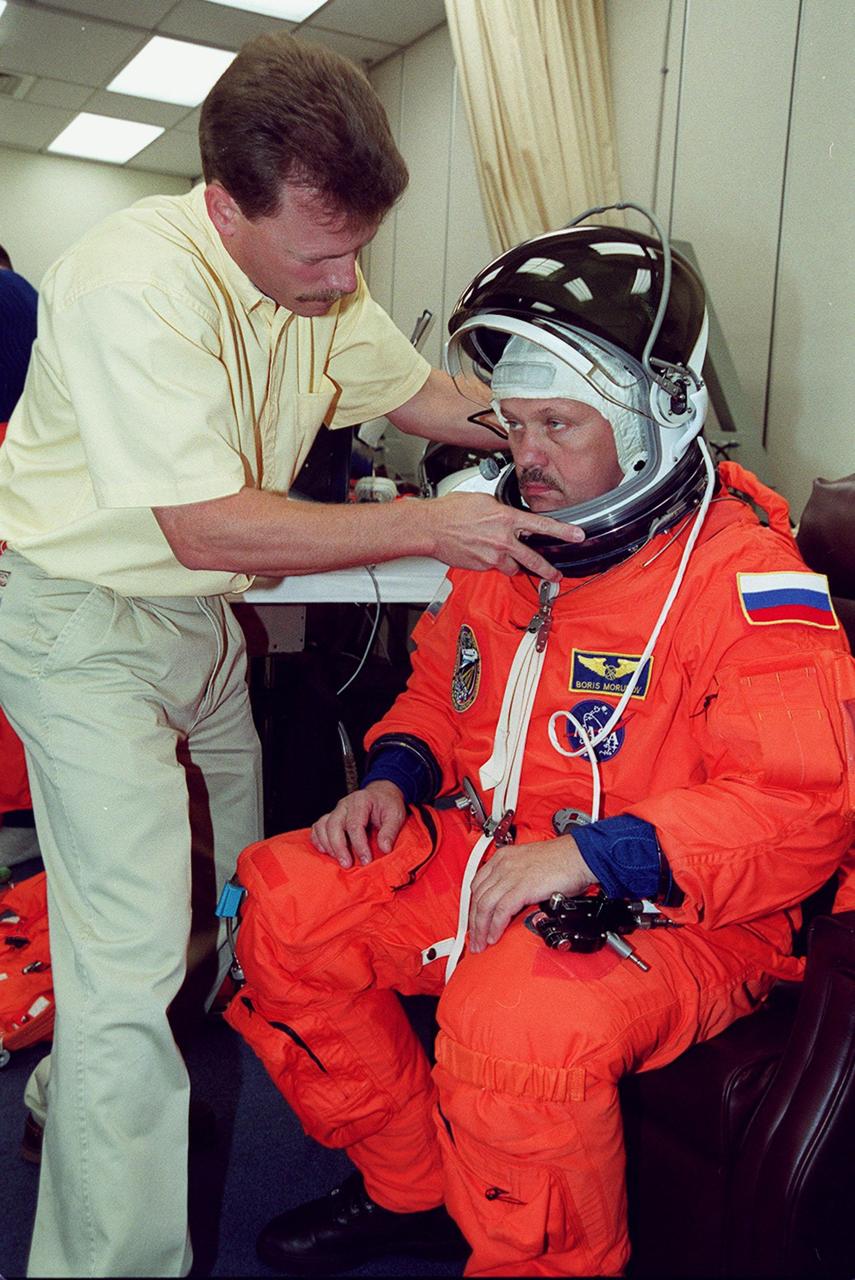 STS-106 Mission Specialist Boris Morukov has his helmet adjusted during fit check, part of Terminal Countdown Demonstration Test activities (TCDT). The TCDT also provides emergency egress training, simulated countdown exercises and opportunities for the crew to inspect the mission payloads in the orbiter’s payload bay. STS-106 is scheduled to launch Sept. 8, 2000, at 8:31 a.m. EDT from Launch Pad 39B. On the 11-day mission, the seven-member crew will perform support tasks on orbit, transfer supplies and prepare the living quarters in the newly arrived Zvezda Service Module. The first long-duration crew, dubbed “Expedition One,” is due to arrive at the Station in late fall