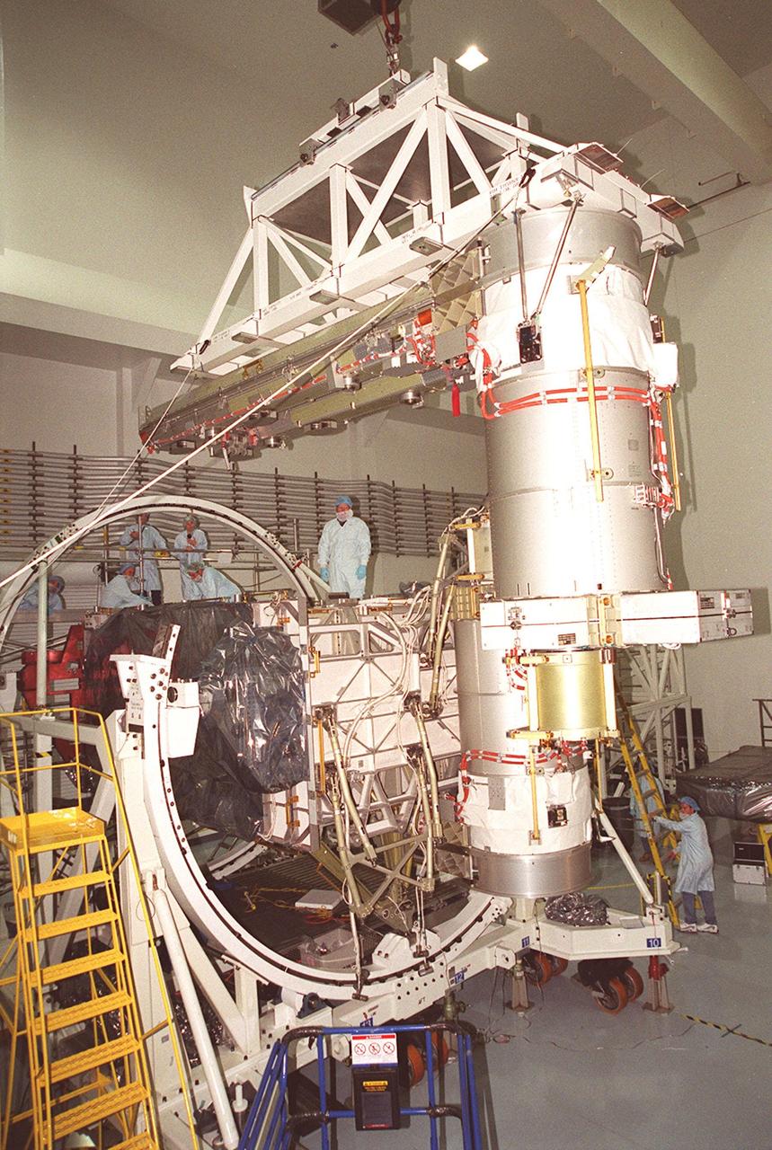 In the Space Station Processing Facility, the overhead crane carrying a solar array maneuvers its cargo into position on the Integrated Equipment Assembly on which it will be installed. Solar Array Wing-3 is already in place. Components of the International Space Station, the arrays are scheduled to be launched on mission STS-97 in late November along with the P6 truss. The Station’s electrical power system (EPS) will use eight photovoltaic solar arrays to convert sunlight to electricity. Each of the eight solar arrays will be 112 feet long by 39 feet wide. The solar arrays are mounted on a “blanket” that can be folded like an accordion for delivery. Once in orbit, astronauts will deploy the blankets to their full size. Gimbals will be used to rotate the arrays so that they will face the Sun to provide maximum power to the Space Station