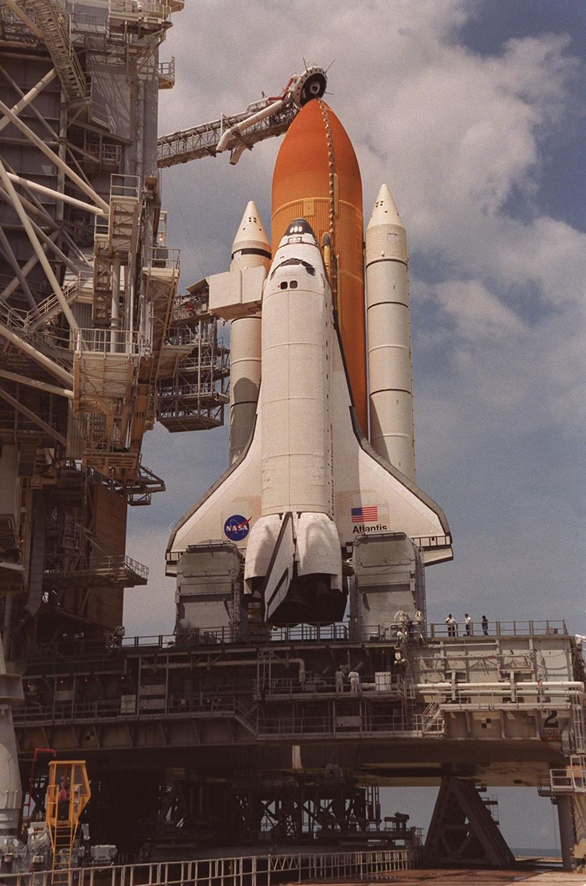 KENNEDY SPACE CENTER, Fla. -- With the Rotating Service Structure rolling back, Space Shuttle Atlantis is revealed on the Mobile Launcher Platform. At the top is the 13-foot-wide “beanie cap,” at the end of the Gaseous Oxygen Vent Arm, designed to vent gaseous oxygen vapors away from the Space Shuttle. Lower is the Orbiter Access Arm with the environmental chamber, known as the “white room,” extended to the orbiter. The chamber provides entry for the crew into the orbiter and also serves as emergency egress up to 7 minutes 24 seconds before launch
