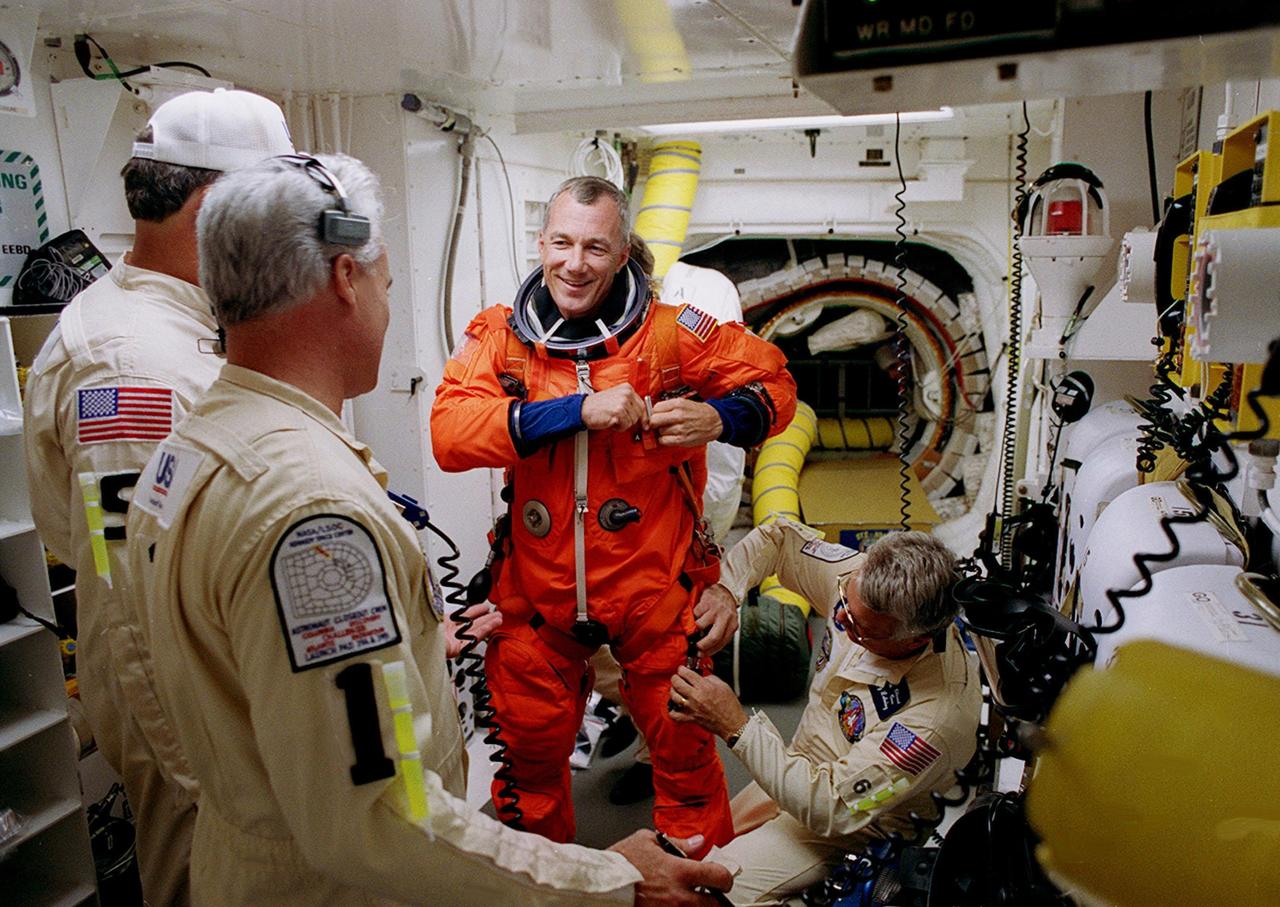 STS-106 Commander Terrence W. Wilcutt gets help with his launch and entry suit from suit technicians in the White Room before he enters Space Shuttle Atlantis. In the background can be seen the opening into Atlantis. The perfect on-time liftoff of Atlantis on mission STS-106 occurred at 8:45:47 a.m. EDT. On the 11-day mission to the International Space Station, the seven-member crew will perform support tasks on orbit, transfer supplies and prepare the living quarters in the newly arrived Zvezda Service Module. The first long-duration crew, dubbed “Expedition One,” is due to arrive at the Station in late fall. Landing of Atlantis is targeted for 4:45 a.m. EDT on Sept. 19