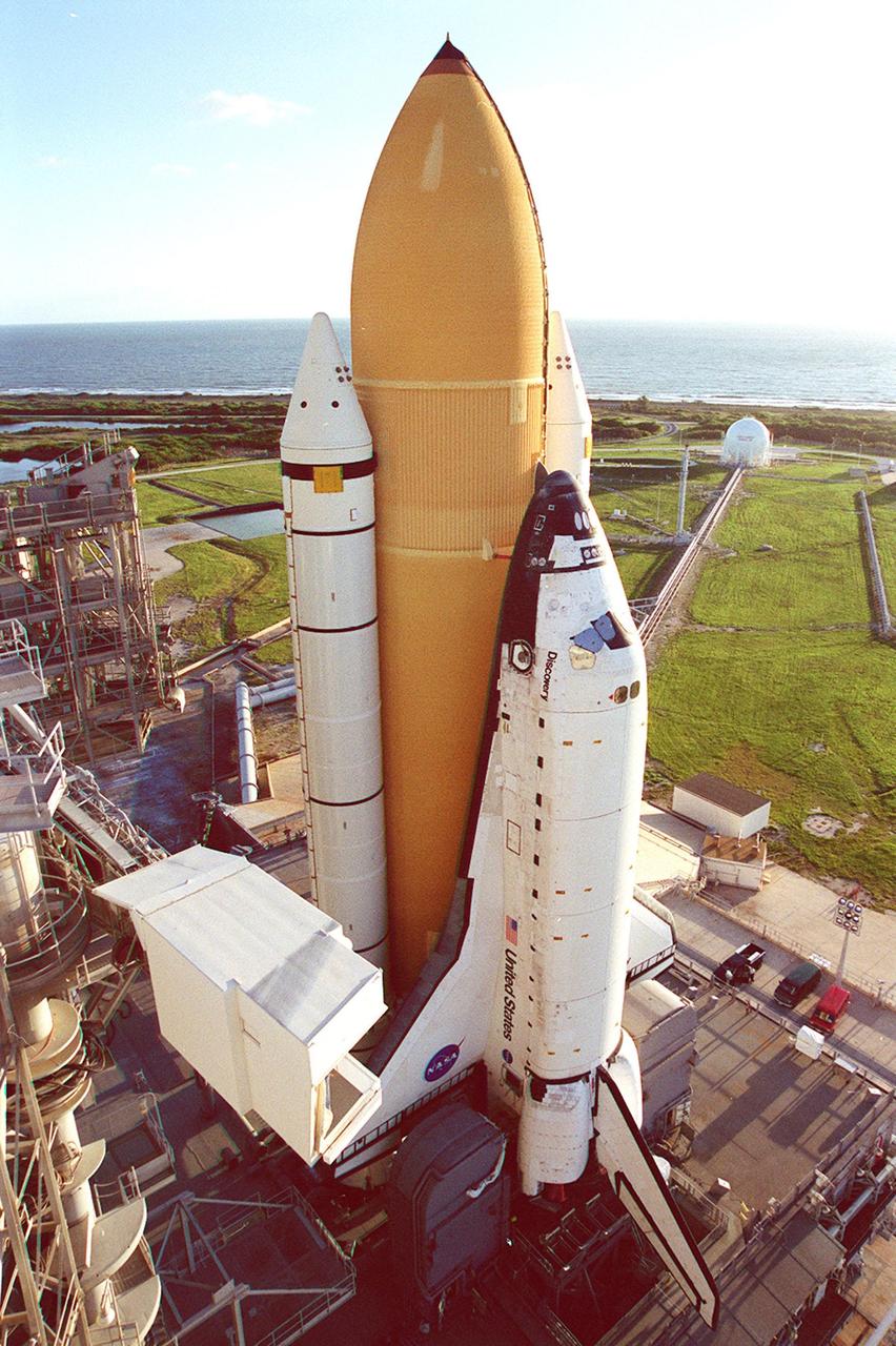 KENNEDY SPACE CENTER, Fla. -- In the bright morning sun, Space Shuttle Discovery towers above the landscape, and cars below, as it sits on Launch Pad 39A. At left can be seen the environmental chamber known as the “white room” that provides access inside the orbiter when it is in place. The white room is at the end of the Orbiter Access Arm, moved away from the Space Shuttle in this photograph. Discovery is scheduled to launch Oct. 5 at 9:30 p.m. EDT on mission STS-92. Making the 100th Space Shuttle mission launched from Kennedy Space Center, Discovery will carry two pieces of hardware for the International Space Station, the Z1 truss, which is the cornerstone truss of the Station, and the third Pressurized Mating Adapter. Discovery also will be making its 28th flight into space, more than any of the other orbiters to date