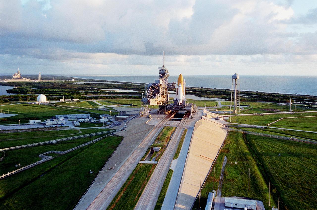 KENNEDY SPACE CENTER, Fla. -- The early morning sun falls on Launch Pad 39A and Space Shuttle Discovery, which is waiting for launch on mission STS-92 Oct. 5, 2000. Leading to the pad (from the foreground) is the ramp leading from the crawlerway, the specially built road that provides the Shuttles access to the pads from the Vehicle Assembly Building. At the right of the pad is the 300,000-gallon water tank that is part of the sound suppression system during launches. Beyond is the Atlantic Ocean. At the far left can be seen Launch Pad 39B with its water tank