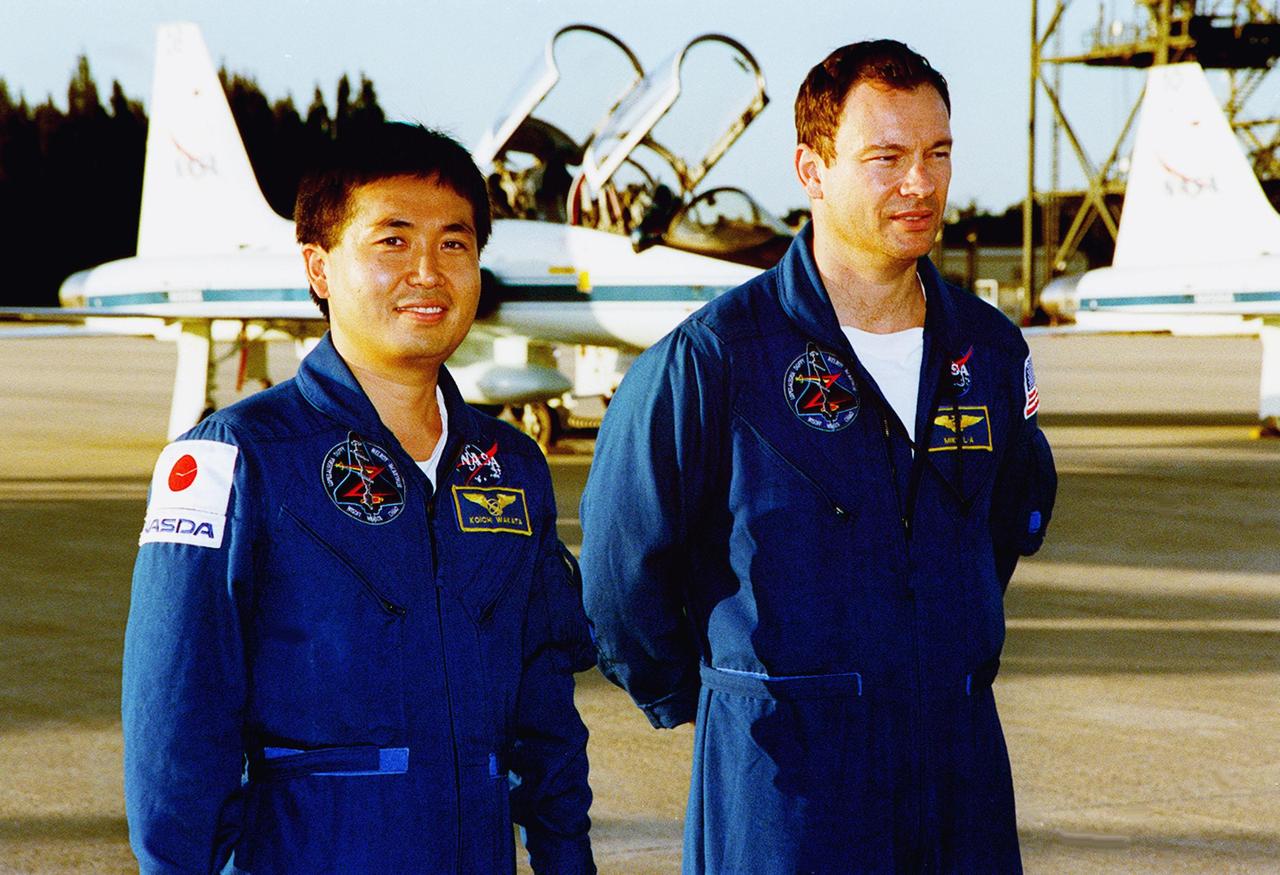 STS-92 Mission Specialists Koichi Wakata and Michael Lopez-Alegria pause on the tarmac after their arrival aboard the T-38 jet aircraft in the background. They and the rest of the crew are at KSC to take part in Terminal Countdown Demonstration Test (TCDT) activities. The TCDT includes emergency egress training from the orbiter and pad, plus a simulated countdown. The fifth mission to the International Space Station, STS-92 will carry the Integrated Truss Structure Z1, the first of the planned 10 trusses on the Space Station, and the third Pressurized Mating Adapter. The Z1 will allow the first U.S. solar arrays on a future flight to be temporarily installed on Unity for early power. PMA-3 will provide a Shuttle docking port for the solar array installation on the sixth ISS flight and Lab installation on the seventh ISS flight. STS-92 is scheduled to launch Oct. 5 from launch Pad 39A. It will be the 100th flight in the Shuttle program