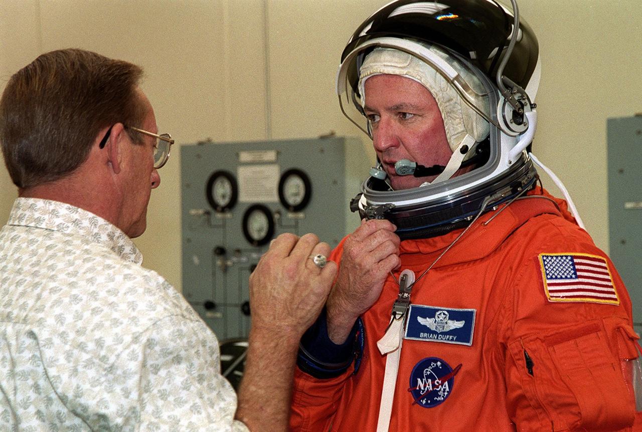 During pre-pack and fit check on his launch and entry suit, STS-92 Commander Brian Duffy adjusts his helmet. Duffy and the rest of the crew are at KSC for Terminal Countdown Demonstration Test activities. The TCDT provides emergency egress training, simulated countdown exercises and opportunities to inspect the mission payload. This mission will be Duffy’s fourth Shuttle flight. STS-92 is scheduled to launch Oct. 5 at 9:38 p.m. EDT from Launch Pad 39A on the fifth flight to the International Space Station. It will carry two elements of the Space Station, the Integrated Truss Structure Z1 and the third Pressurized Mating Adapter. The mission is also the 100th flight in the Shuttle program
