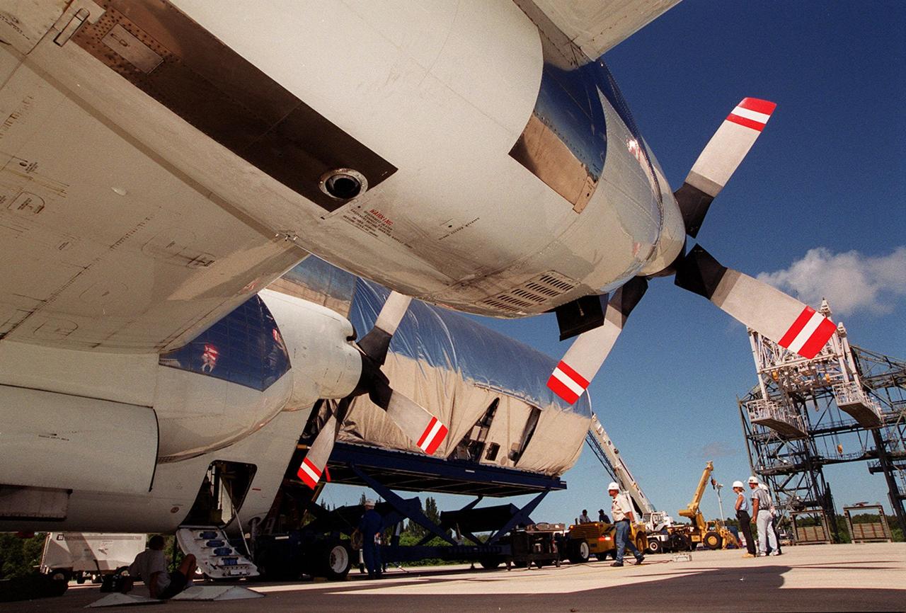KENNEDY SPACE CENTER, FLA. -- Viewed from underneath the wing of NASA’s Super Guppy aircraft, the Joint Airlock Module, the gateway from which crew members aboard the International Space Station (ISS) will enter and exit the 470-ton orbiting research facility, rolls out of the aircraft.  It will be transferred to the Operations and Checkout Building in the KSC industrial area where it will undergo vacuum chamber testing. Then it will be moved to the Space Station Processing Facility (SSPF) for further pre-launch preparation and checkout. The massive, spindle-shaped airlock is 20 feet long, has a diameter of 13 feet at its widest point, and weighs six and a half tons. It was manufactured at NASA's Marshall Space Flight Center by the Huntsville division of The Boeing Company. The Space Shuttle Atlantis will carry the airlock to orbit on mission STS-104, the tenth International Space Station flight, currently targeted for liftoff in May 2001