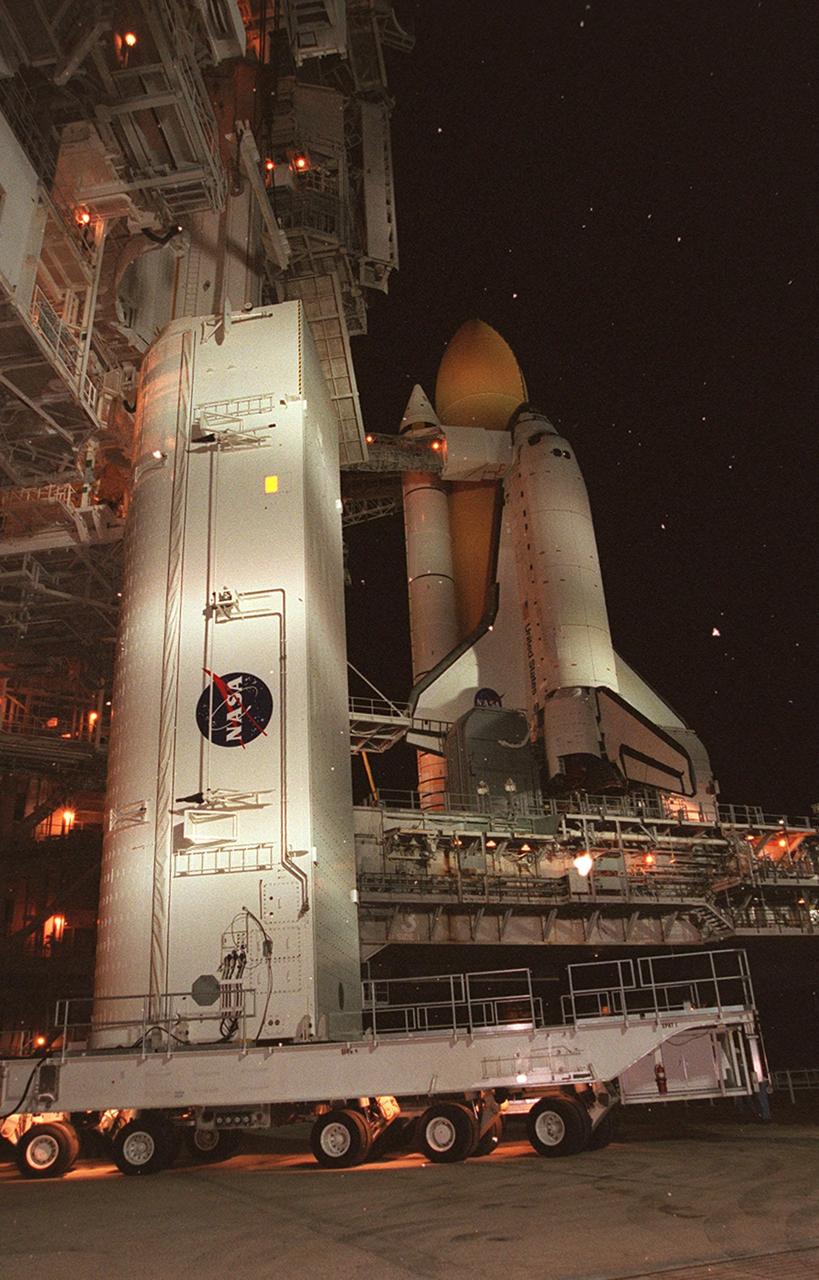KENNEDY SPACE CENTER, Fla. --  At Launch Pad 39A, the payload canister with the Integrated Truss Structure Z1 inside arrives at the spot under the Rotating Service Structure where the canister can be lifted to the Payload Changeout Room. There the Z1 truss will be removed and later transferred to Space Shuttle Discovery’s payload bay. Discovery is at right, sitting atop the Mobile Launcher Platform. The Z1 truss is the first of 10 that will become the backbone of the International Space Station, eventually stretching the length of a football field. Along with its companion payload, the third Pressurized Mating Adapter, the Z1 is scheduled to be launched aboard Discovery Oct. 5 at 9:38 p.m. EDT