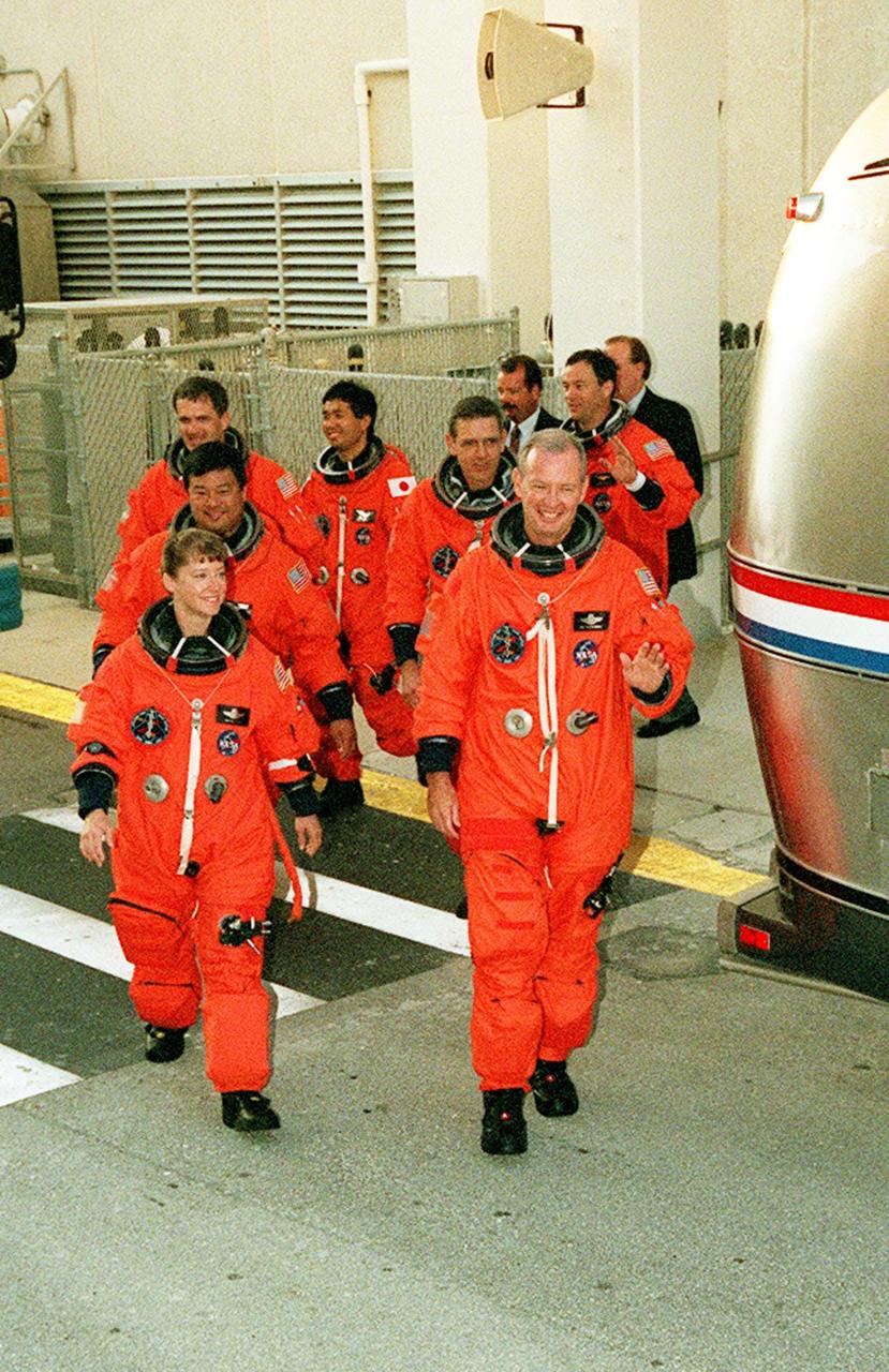 The STS-92 crew exits the Operations and Checkout Building on their way to the Astrovan and Launch Pad 39A for a simulated countdown. On the left, front to back, are Pilot Pamela Ann Melroy and Mission Specialists Leroy Chiao, Peter J.K. “Jeff” Wisoff, and Koichi Wakata of Japan. On the right, front to back, are Commander Brian Duffy and Mission Specialists William S. McArthur Jr. and Michael E. Lopez-Alegria. The crew is taking part in Terminal Countdown Demonstration Test activities that provide emergency egress training, opportunities to inspect the mission payload, and the simulated countdown. STS-92 is scheduled to launch Oct. 5 at 9:38 p.m. EDT on the fifth flight to the International Space Station. It will carry two elements of the Space Station, the Integrated Truss Structure Z1 and the third Pressurized Mating Adapter. The mission is also the 100th flight in the Shuttle program