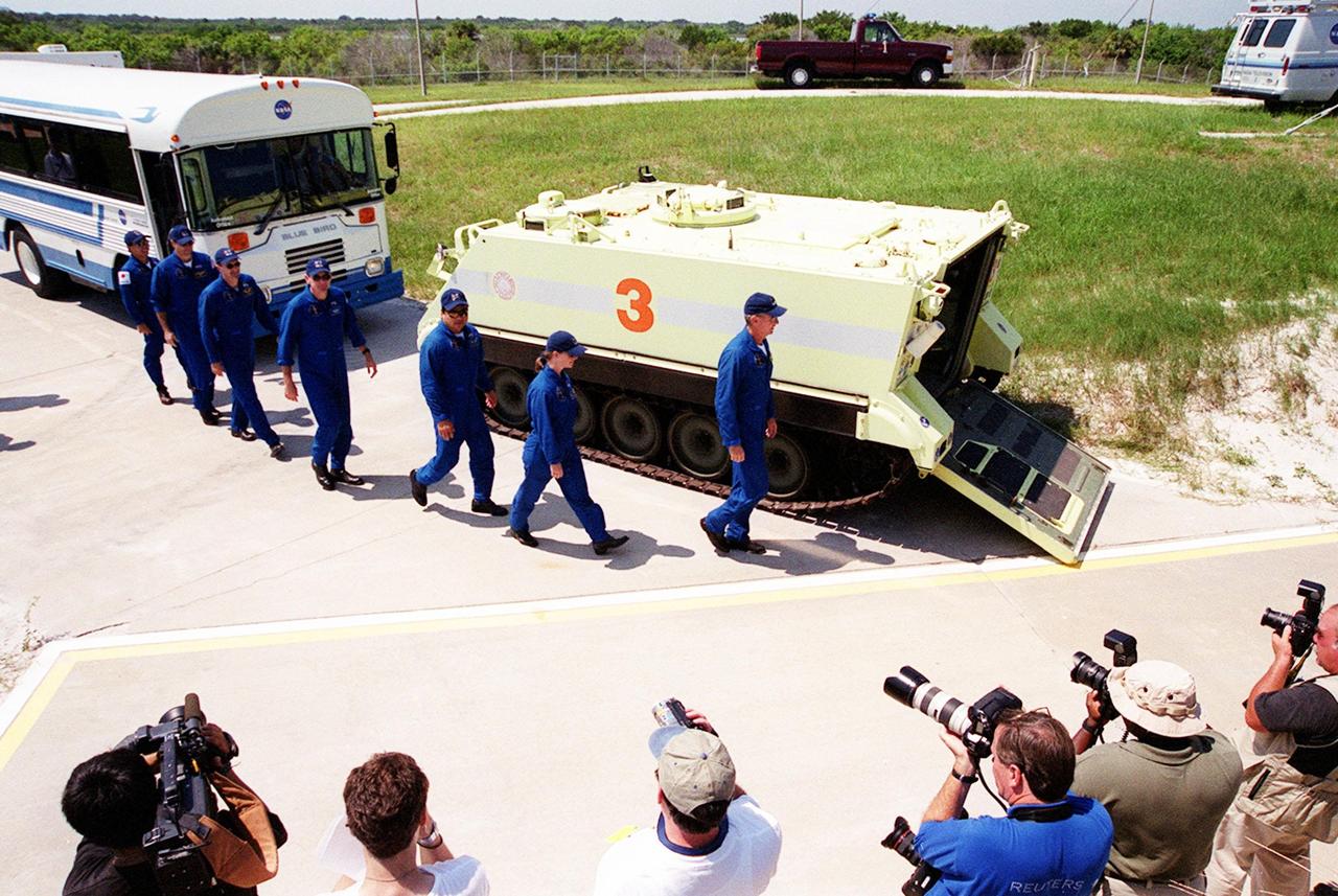 KENNEDY SPACE CENTER, FLA. -- The STS-92 crew heads toward the slidewire basket area at Launch Pad 39A for a question and answer session with the media. From left to right are Mission Specialists Koichi Wakata of Japan, Michael E. Lopez-Alegria, Peter J.K. “Jeff” Wisoff, William S. McArthur Jr., and Leroy Chiao; Pilot Pamela Ann Melroy; and Commander Brian Duffy. Photographers in the foreground record the activity. The crew is at KSC for Terminal Countdown Demonstration Test activities that provide emergency egress training, opportunities to inspect the mission payload, and a simulated countdown. The slidewire basket area is a landing site for the crew if they have to use the slidewire baskets to exit the orbiter on the pad in an emergency. STS-92 is scheduled to launch Oct. 5 at 9:38 p.m. EDT on the fifth flight to the International Space Station. It will carry two elements of the Space Station, the Integrated Truss Structure Z1 and the third Pressurized Mating Adapter. The mission is also the 100th flight in the Shuttle program