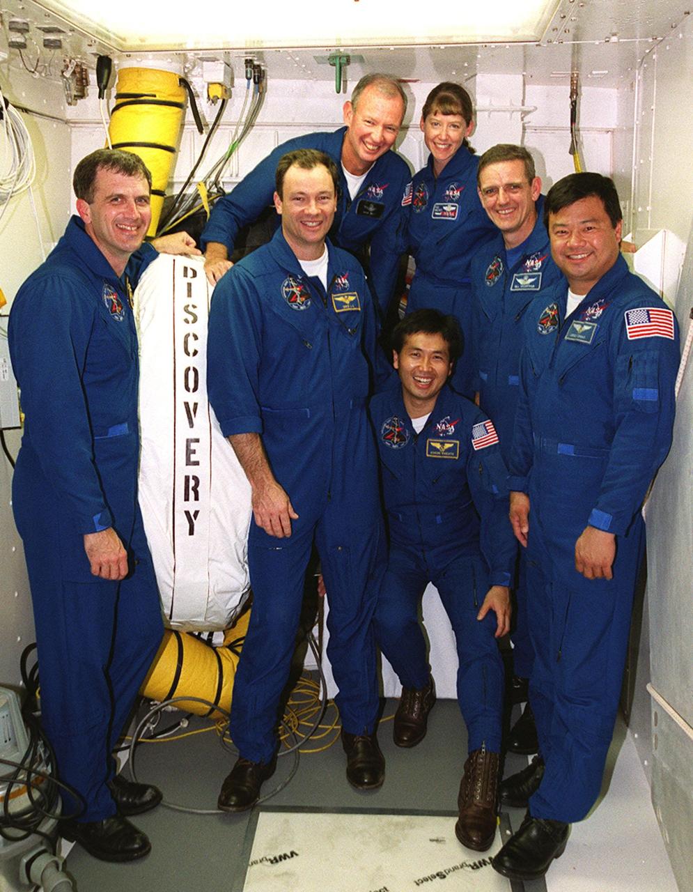 The STS-92 crew poses for a photograph in the White Room, the environmentally controlled chamber on the orbiter access arm that provides entry for the crew into the orbiter. Standing, left to right, are Mission Specialists Peter J.K. “Jeff” Wisoff and Michael E. Lopez-Alegria; Commander Brian Duffy; Pilot Pamela Ann Melroy; and Mission Specialists William S. McArthur Jr. and Leroy Chiao. Crouching in front is Mission Specialist Koichi Wakata of Japan. The crew is at KSC for Terminal Countdown Demonstration Test activities that provide emergency egress training, opportunities to inspect the mission payload, and take part in a simulated countdown. STS-92 is scheduled to launch Oct. 5 at 9:38 p.m. EDT on the fifth flight to the International Space Station. It will carry two elements of the Space Station, the Integrated Truss Structure Z1 and the third Pressurized Mating Adapter. The mission is also the 100th flight in the Shuttle program