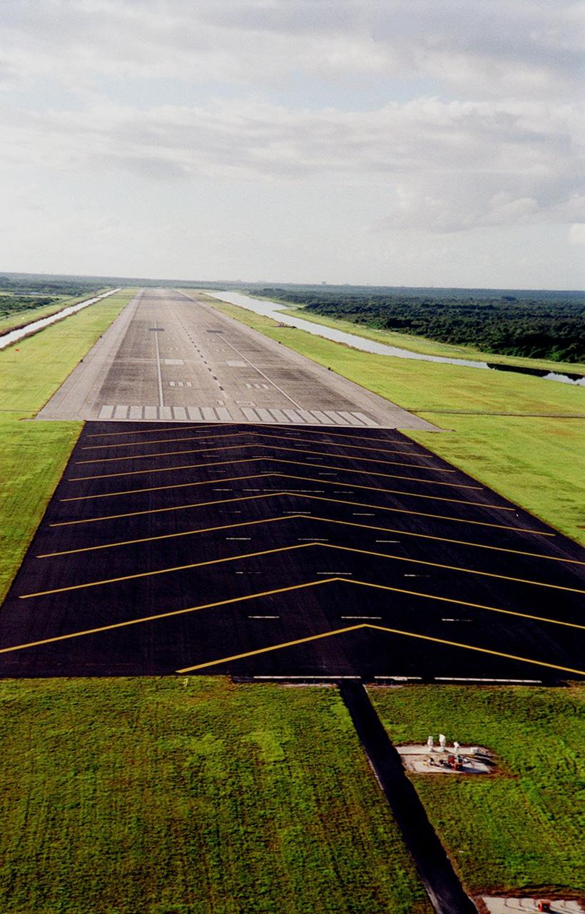 KENNEDY SPACE CENTER, FLA. -- This aerial view shows the approach on Runway 33 at the KSC Shuttle Landing Facility. The runway is 15,000 feet long, with 1,000-foot paved overruns at each end; 300 feet wide (about length of football field), with 50-foot asphalt shoulders each side; 16 inches thick in the center, and 15 inches thick on sides. It has a slope of 24 inches from the center line to the edge for drainage. The single landing strip is considered two runways, depending on approach Runway 15 from northwest, Runway 33 from southeast
