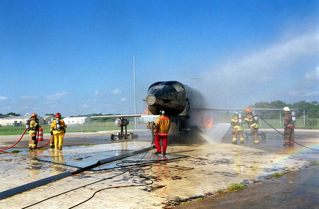 KENNEDY SPACE CENTER, FLA. --  Firefighters surround a burning simulated aircraft during training exercises Cape Canaveral Air Force Station Pad 30. Those at left wait their turn as the crew on the right turn their hoses toward the fire. The firefighters are with Fire and Emergency Services at the Naval Station Mayport, Fla