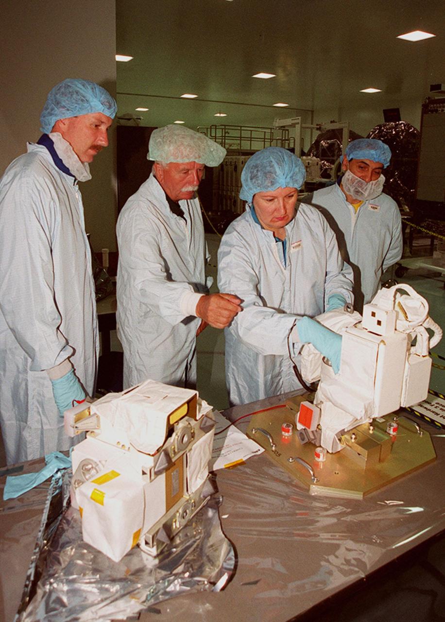 Workers (center) in the Space Station Processing Facility, explain use of video cameras to members of the STS-100 crew (far left and far right) during Crew Equipment Interface Test activities. The cameras will be mounted on the booms and end effectors of the Space Station Remote Manipulator System (SSRMS), also known as the Canadian arm, and will give astronauts maximum visibility for operations and maintenance tasks on the International Space Station. Part of the payload on mission STS-100, the SSRMS is the primary means of transferring payloads between the orbiter payload bay and the International Space Station for assembly. The 56-foot-long robotic arm includes two 12-foot booms joined by a hinge. Seven joints on the arm allow highly flexible and precise movement. Mission STS-100 is scheduled to launch April 19, 2001