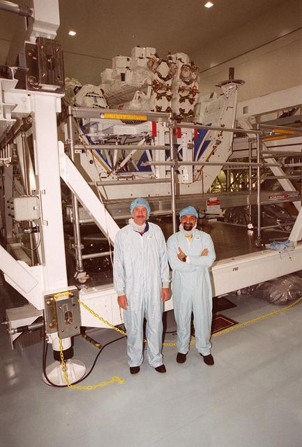 STS-100 Commander Kent Rominger and Mission Specialist Umberto Guidoni (right), with the European Space Agency, pose for a photo during Crew Equipment Interface Test activities in the Space Station Processing Facility. Behind them is the Space Station Remote Manipulator System (SSRMS), also known as the Canadian arm, which is part of the payload on their mission. The SSRMS is the primary means of transferring payloads between the orbiter payload bay and the International Space Station for assembly. The 56-foot-long robotic arm includes two 12-foot booms joined by a hinge. Seven joints on the arm allow highly flexible and precise movement. The payload also includes the Multi-Purpose Logistics Module (MPLM) Raffaello. MPLMs are pressurized modules that will serve as the International Space Station's “moving vans,” carrying laboratory racks filled with equipment, experiments and supplies to and from the station aboard the Space Shuttle. Mission STS-100 is scheduled to launch April 19, 2001