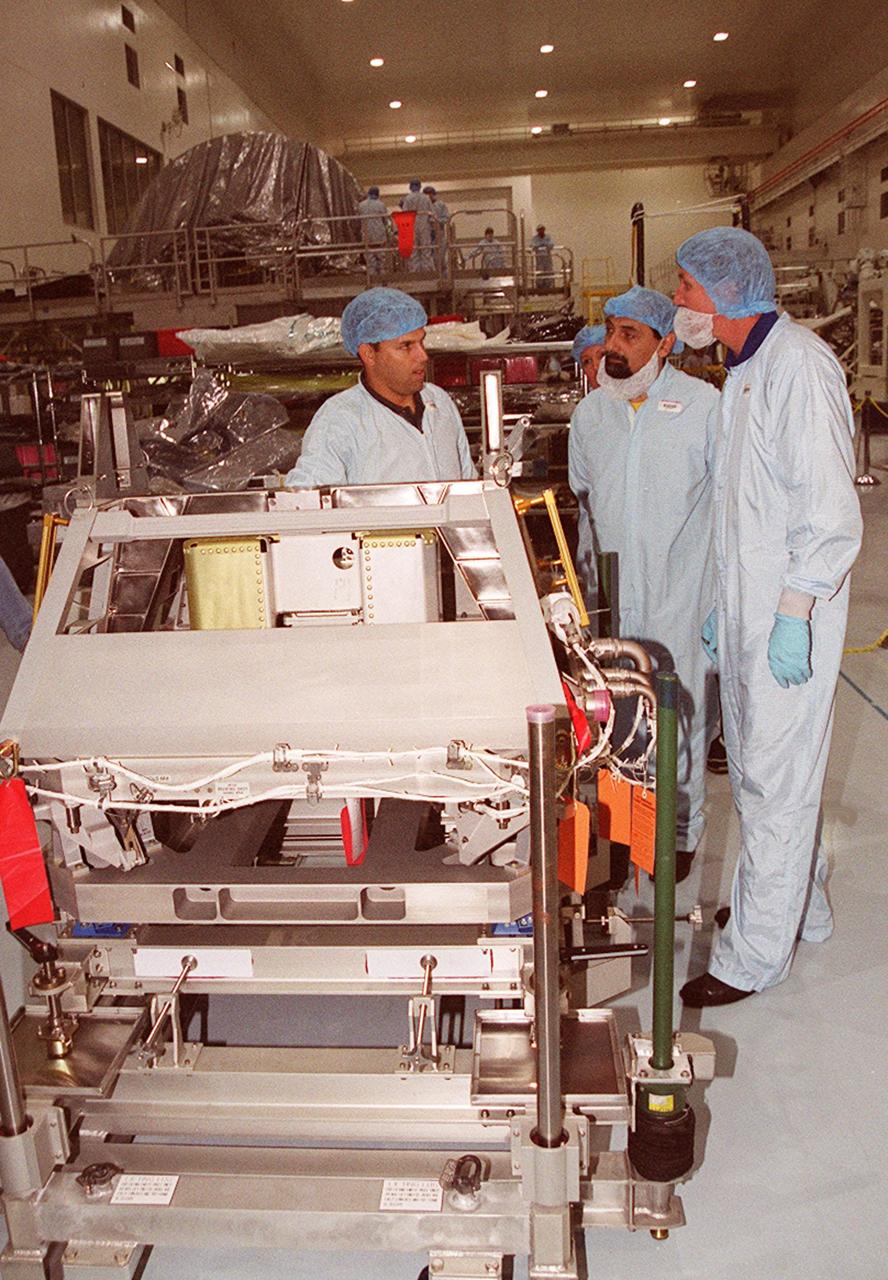 A worker (left) in the Space Station Processing Facility explains use of the equipment in the foreground to STS-100 Mission Specialist Umberto Guidoni (center) and Commander Kent Rominger (right). Guidoni is with the European Space Agency. Mission STS-100, scheduled to launch April 19, 2001, will include the Multi-Purpose Logistics Module (MPLM) Raffaello and the Space Station Remote Manipulator System (SSRMS) as its payload. MPLMs are pressurized modules that will serve as the International Space Station's “moving vans,” carrying laboratory racks filled with equipment, experiments and supplies to and from the station aboard the Space Shuttle. The SSRMS is the primary means of transferring payloads between the orbiter payload bay and the International Space Station for assembly