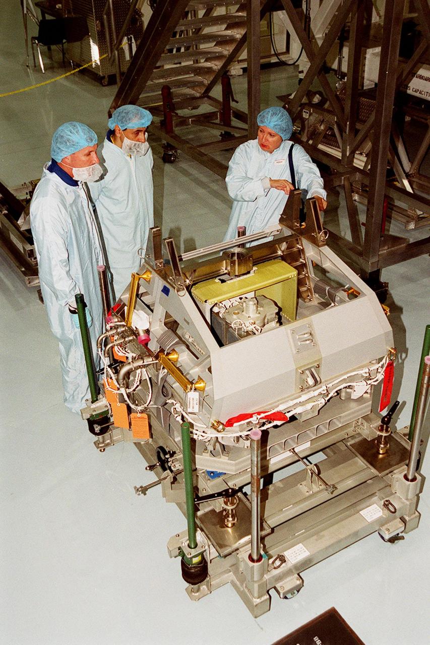 In the Space Station Processing Facility, STS-100 Commander Kent Rominger and Mission Specialist Umberto Guidoni, who is with the European Space Agency, look over equipment on the floor. Mission STS-100, scheduled to launch April 19, 2001, will include the Multi-Purpose Logistics Module (MPLM) Raffaello and the Space Station Remote Manipulator System (SSRMS) as its payload. MPLMs are pressurized modules that will serve as the International Space Station's “moving vans,” carrying laboratory racks filled with equipment, experiments and supplies to and from the station aboard the Space Shuttle. The SSRMS is the primary means of transferring payloads between the orbiter payload bay and the International Space Station for assembly